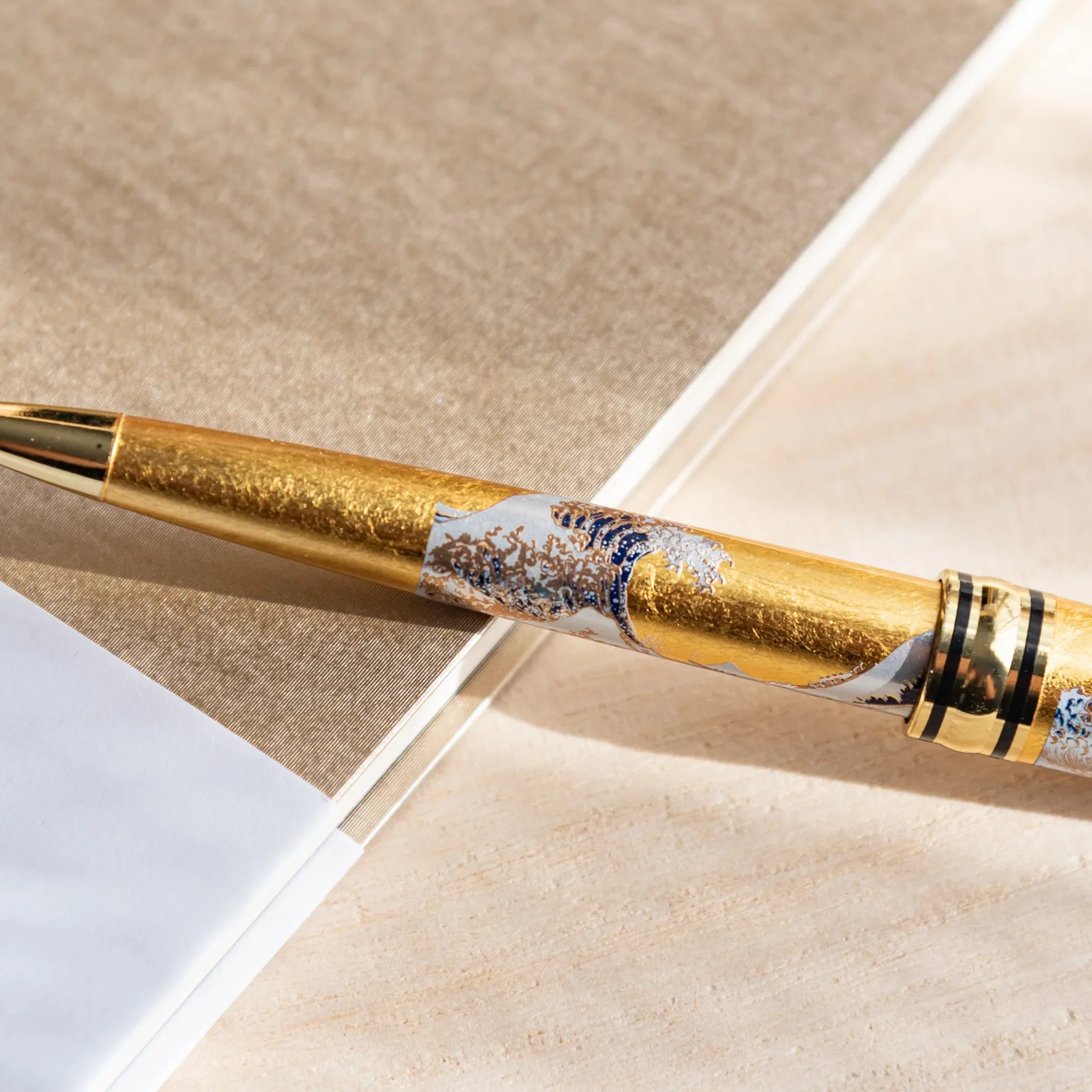Retractable ballpoint featuring gold leaf and Great Wave maki-e design composition shown with gold trim accents