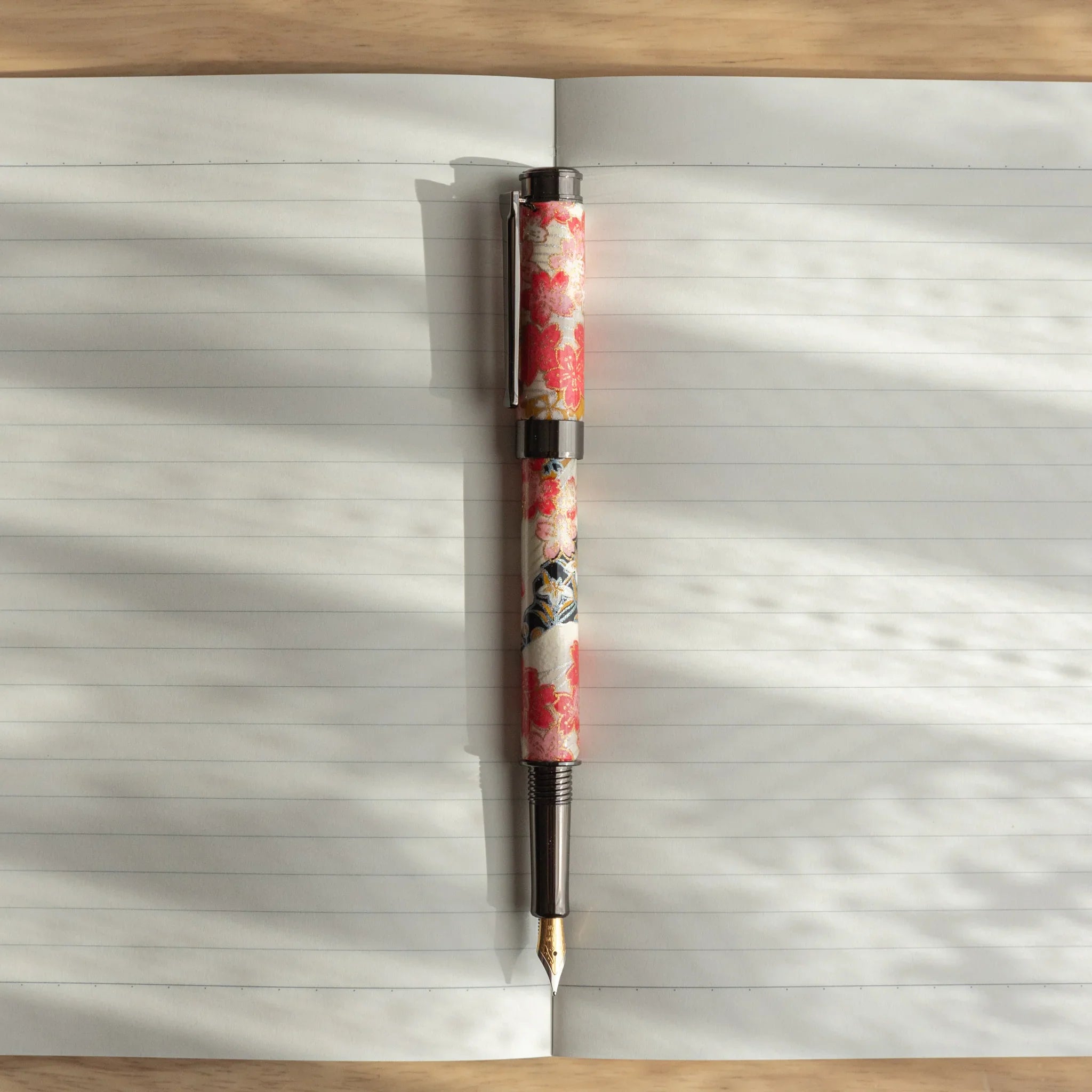 Akebono Cherry Mino Washi fountain pen displaying red flowers and gold metallic decorative components angled view