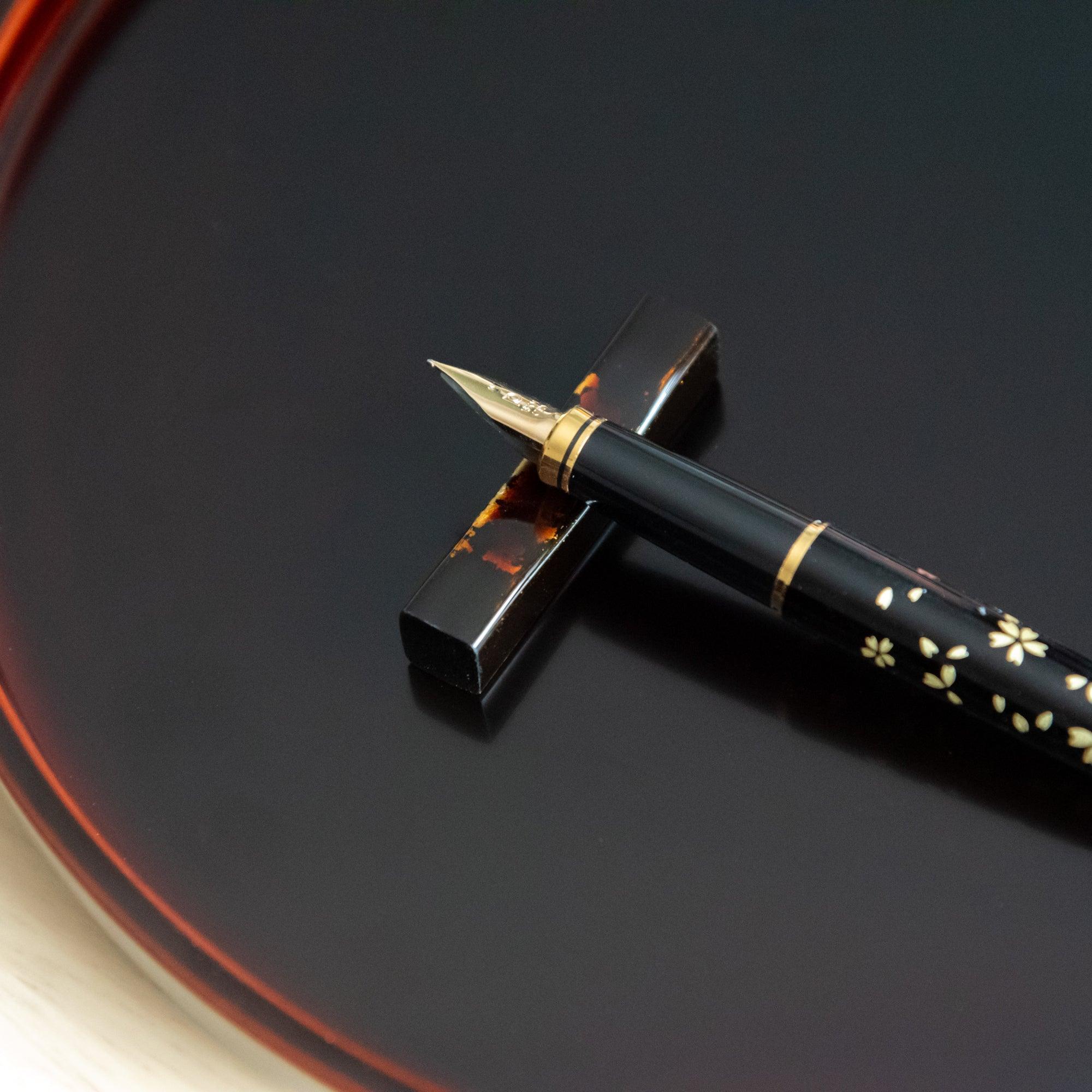 Black Echizen lacquered sakura wood pen rest features gold flecks with precious metal accents, keeping pens secure during
