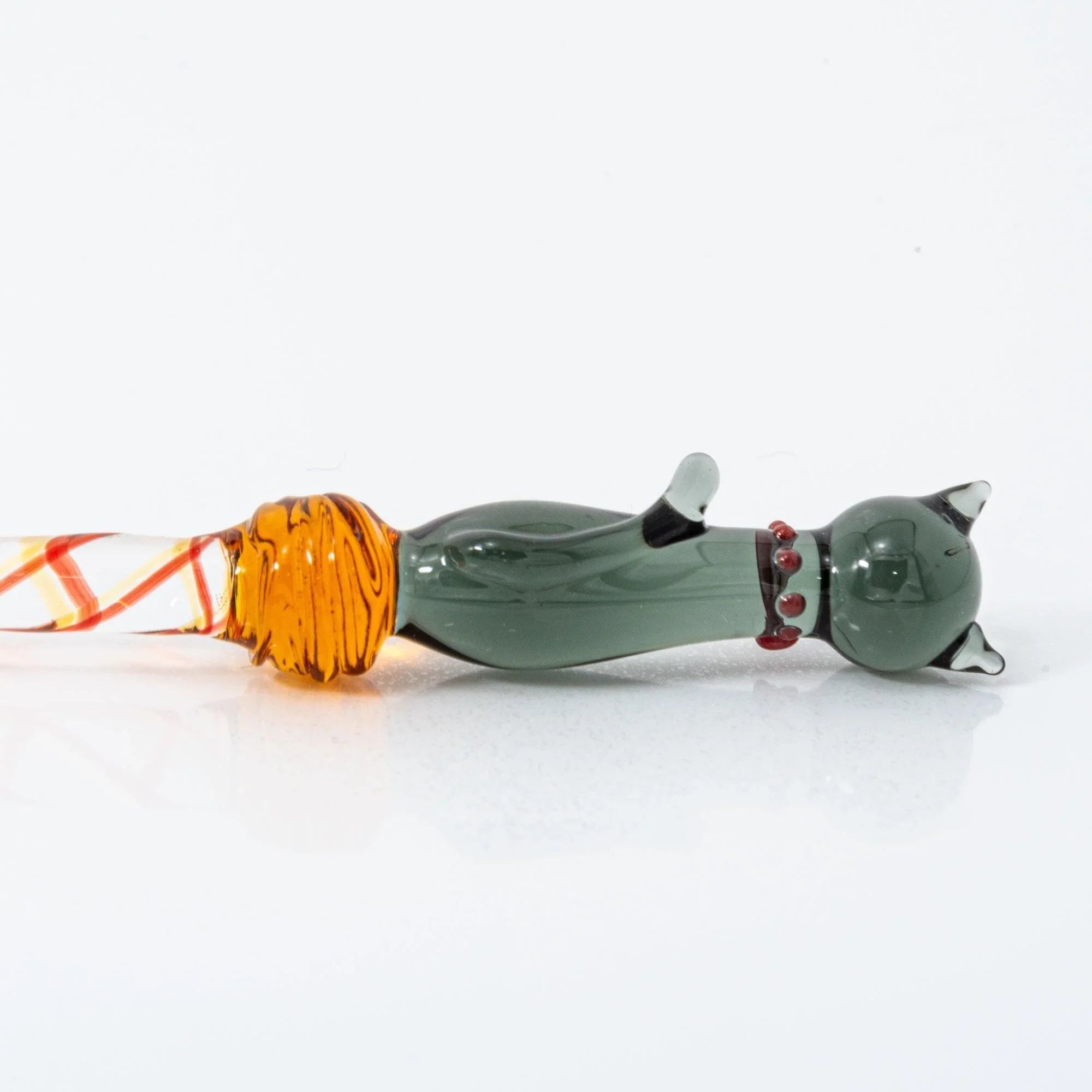 Black Nyanko cat detail with dark green figurine sitting on glass dip pen with colorful striped bands