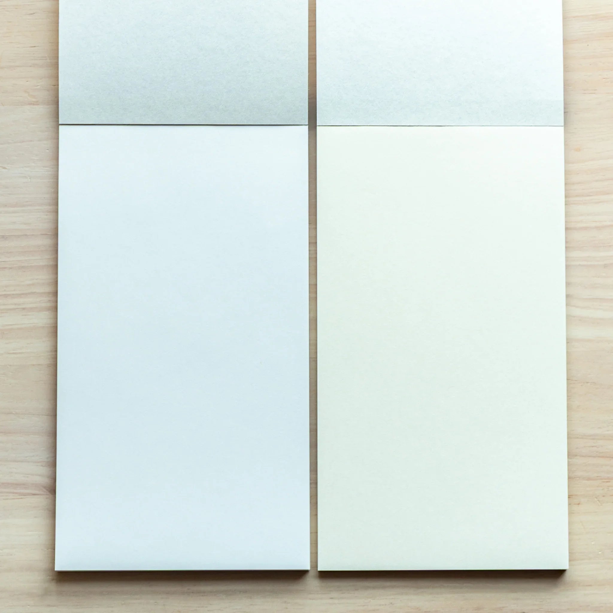 Two Bullet Jotter writing pads side by side on light wood: left with light blue-tinted paper, right with cream-white paper