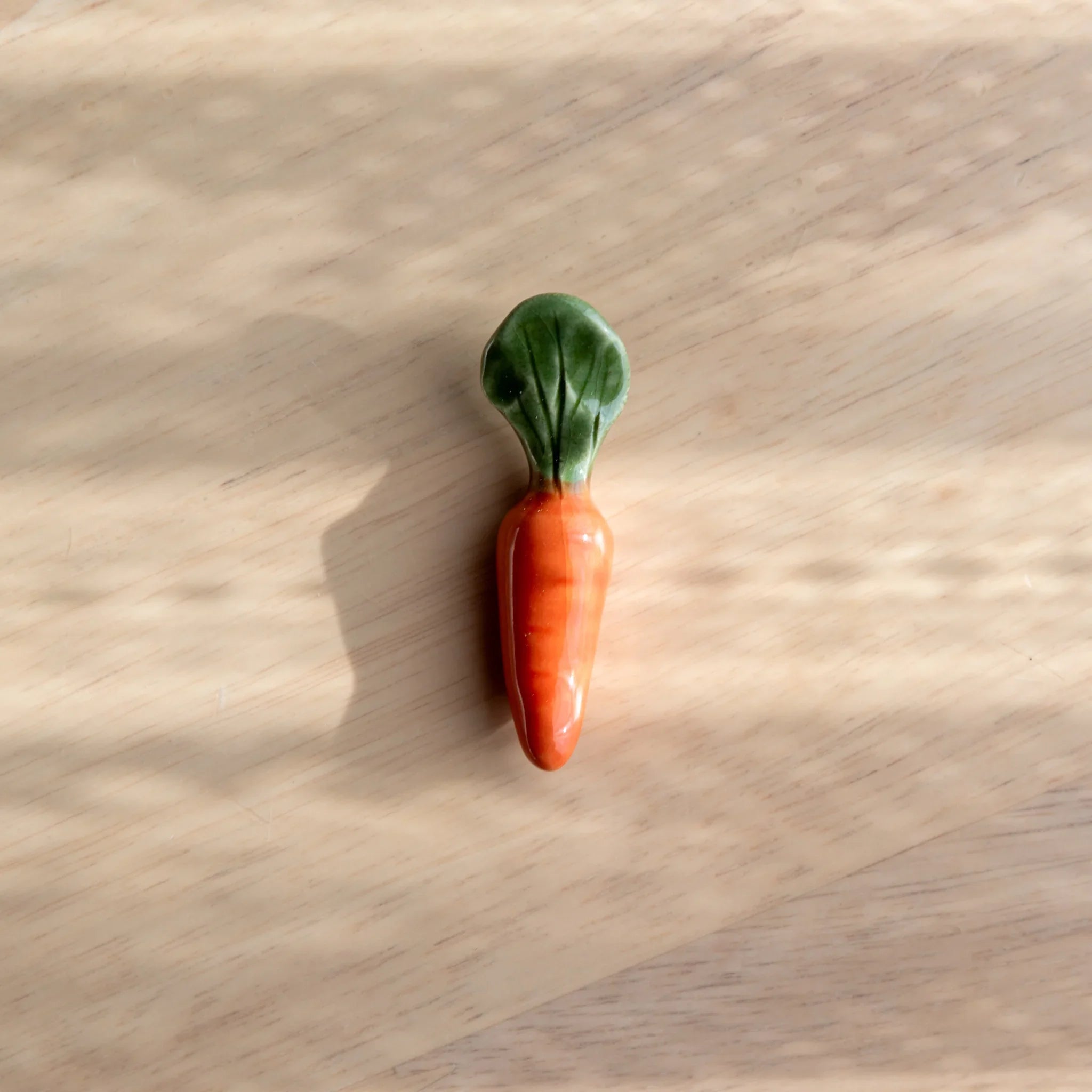 Bright orange carrot-shaped Japanese handcrafted ceramic pen rest with tapered vegetable form overall partially unrolled