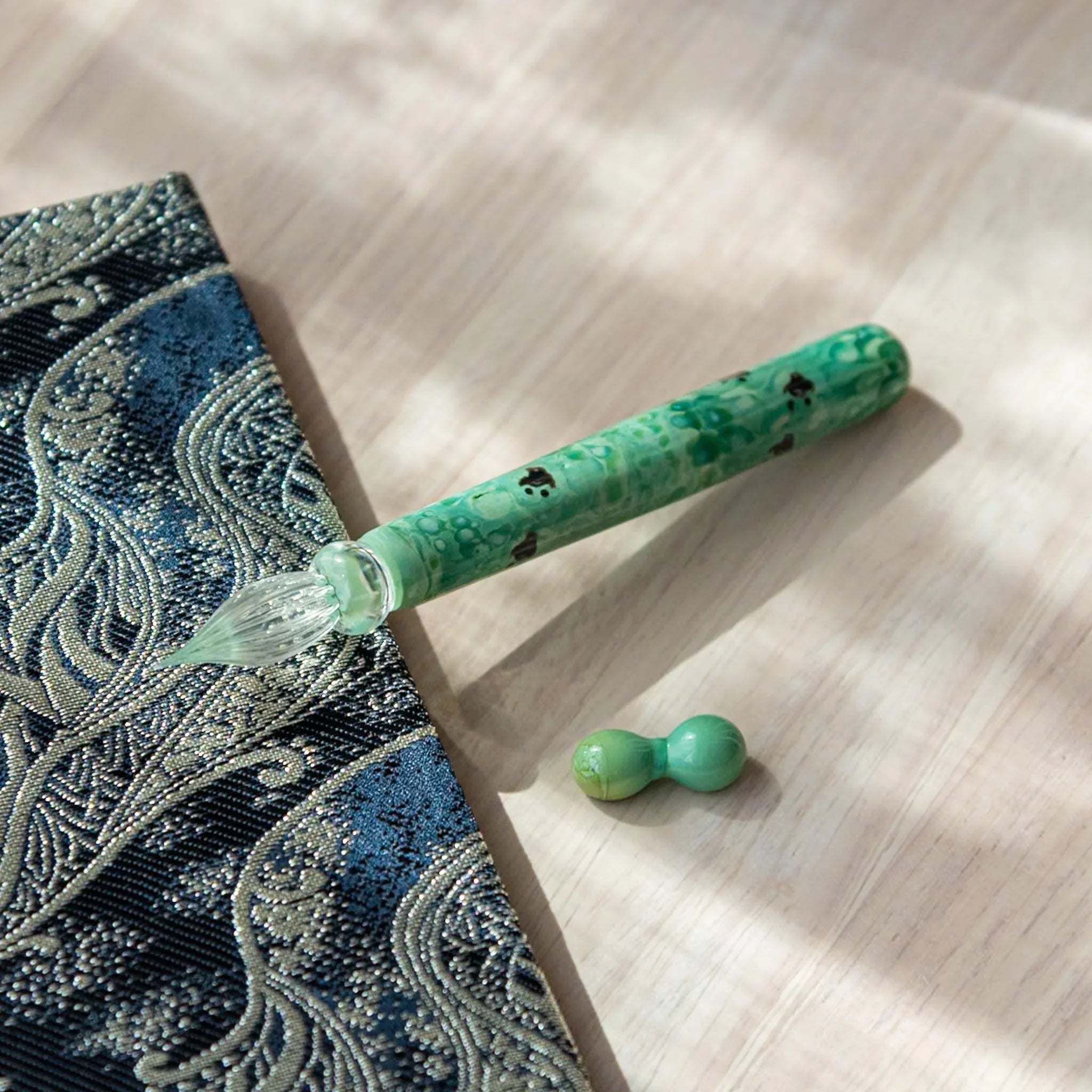 Detailed view of emerald glass dip pen barrel showing dark chidori bird pattern through transparent glass material