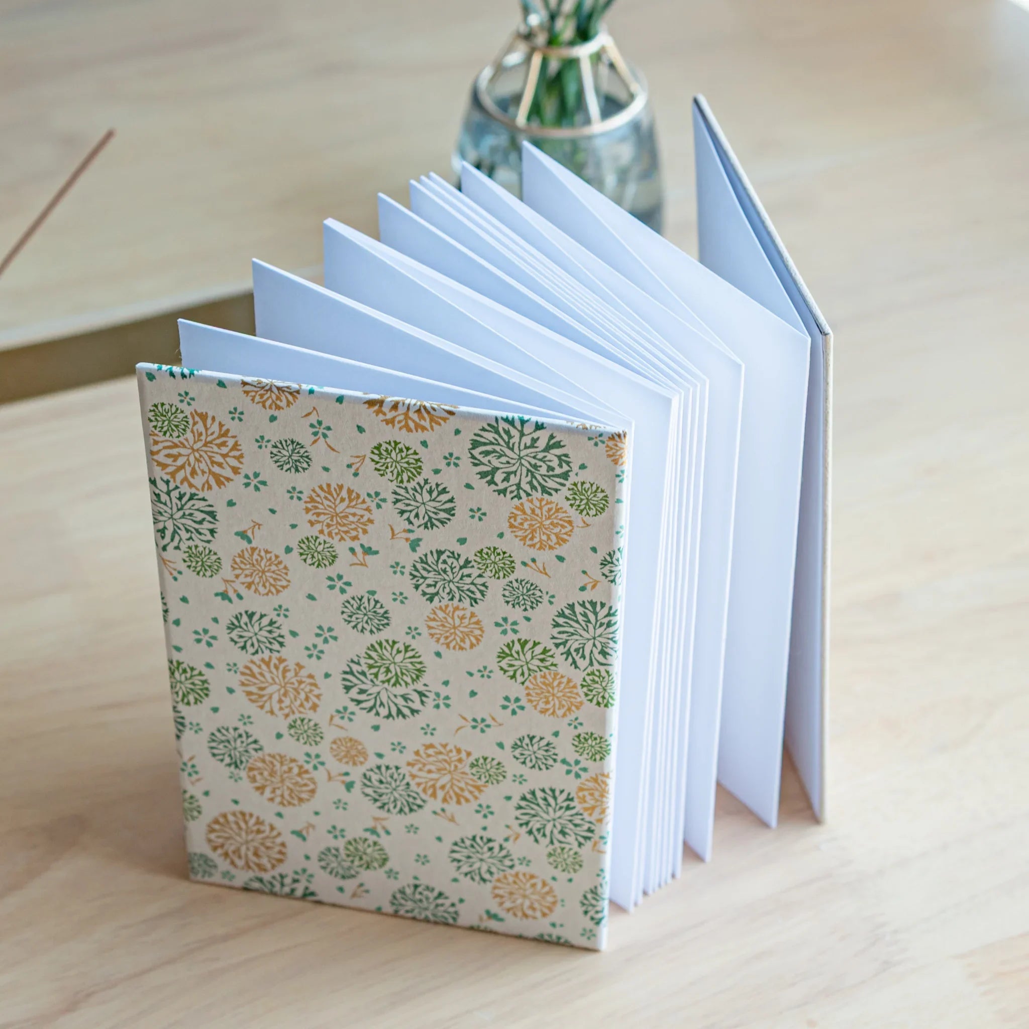 Open Chrysanthemum Harmony green goshuincho showing white interior pages and decorative floral cover design