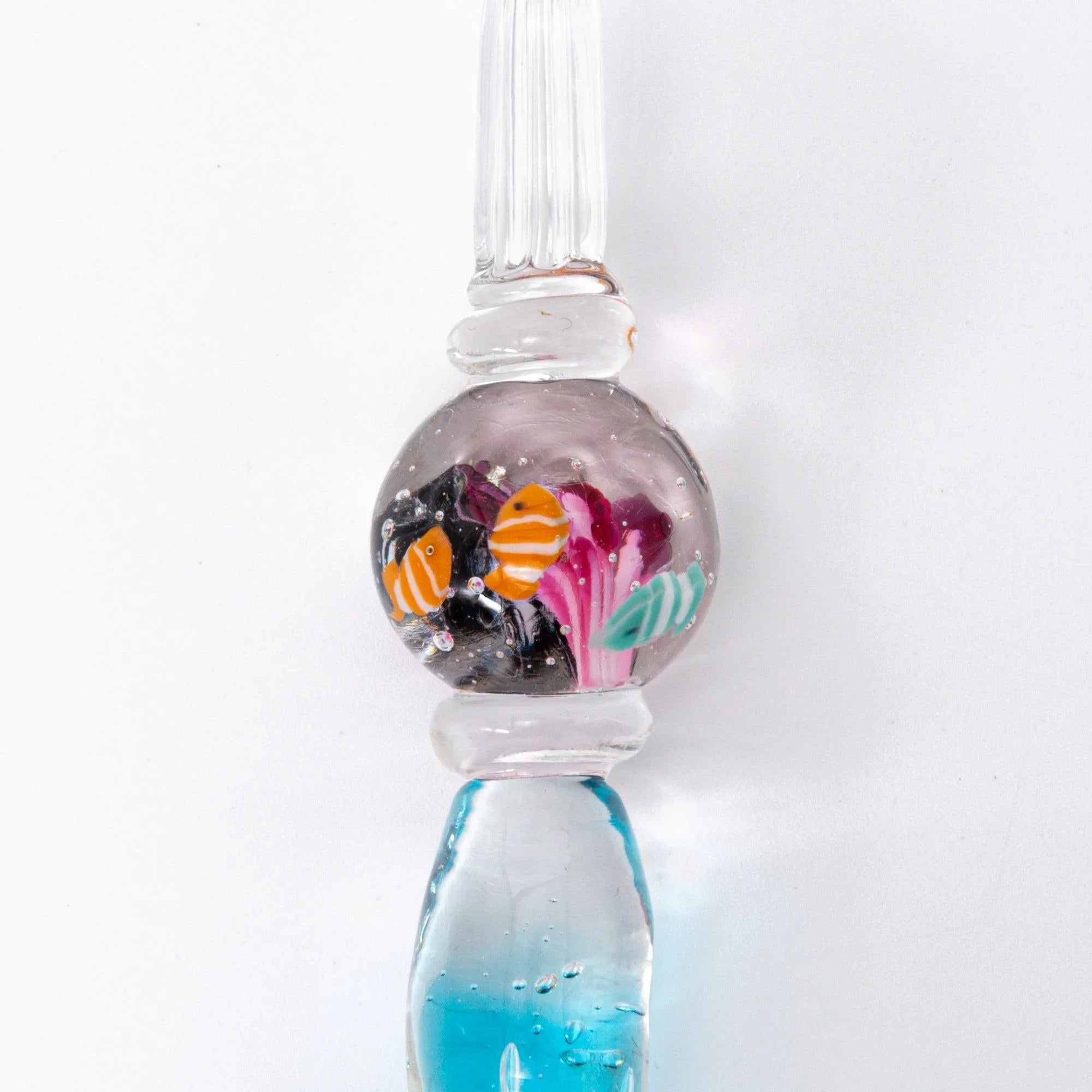 Clownfish aquarium pen detail showing gray-tinted glass sphere with tropical fish and plant elements
