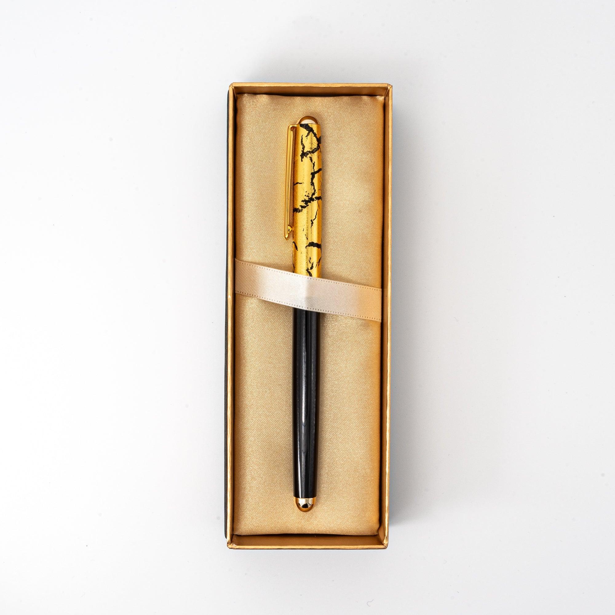 Extreme close-up of Japanese black ballpoint pen and gold crackle cap showing surface texture detail