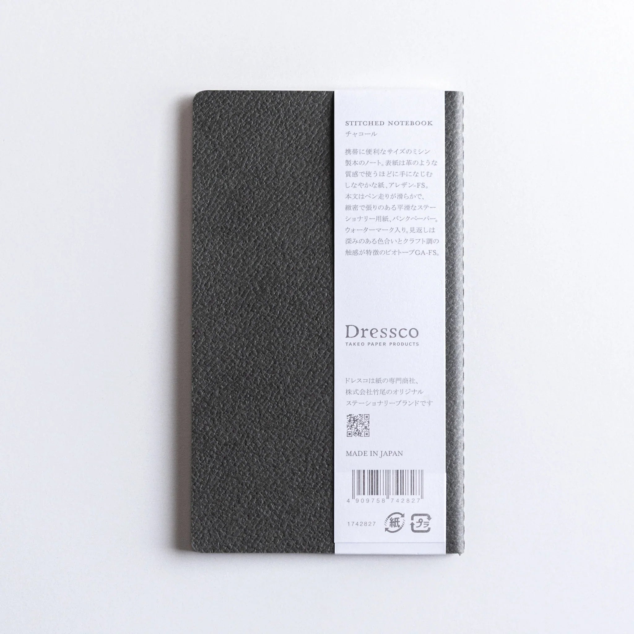 Orange Dressco notebook lying flat on surface showing spine detail and stitched binding construction along notebook edge