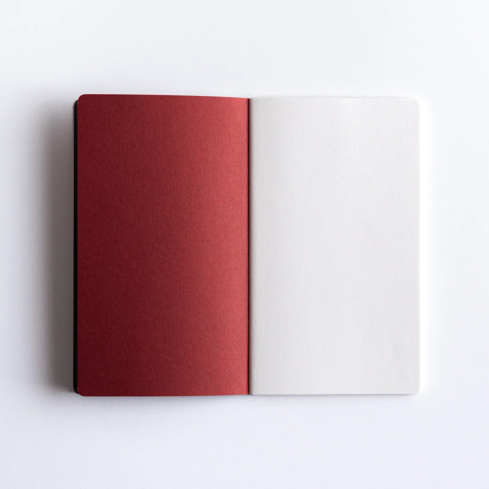Closed view of orange Dressco A6 stitched notebook showing embossed bird logo design clearly on front cover surface