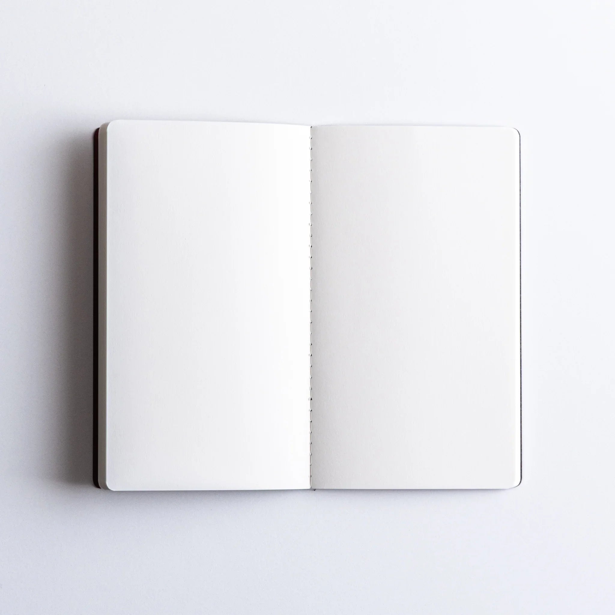 Inside cover pages of charcoal Dressco A6 notebook showing endpaper and stitched binding construction and quality