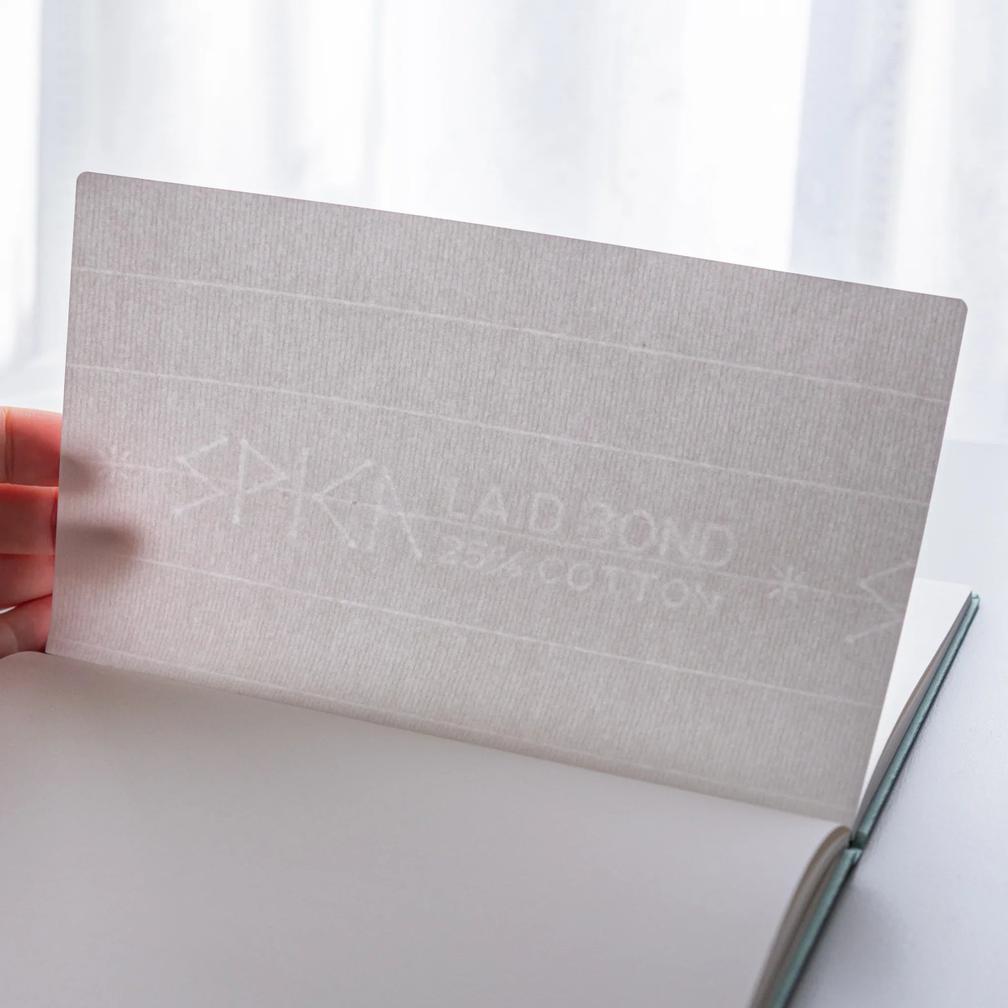 Dressco Spica Laid Bond Paper B6 notebook in a styled desk composition alongside writing pens and daily accessories