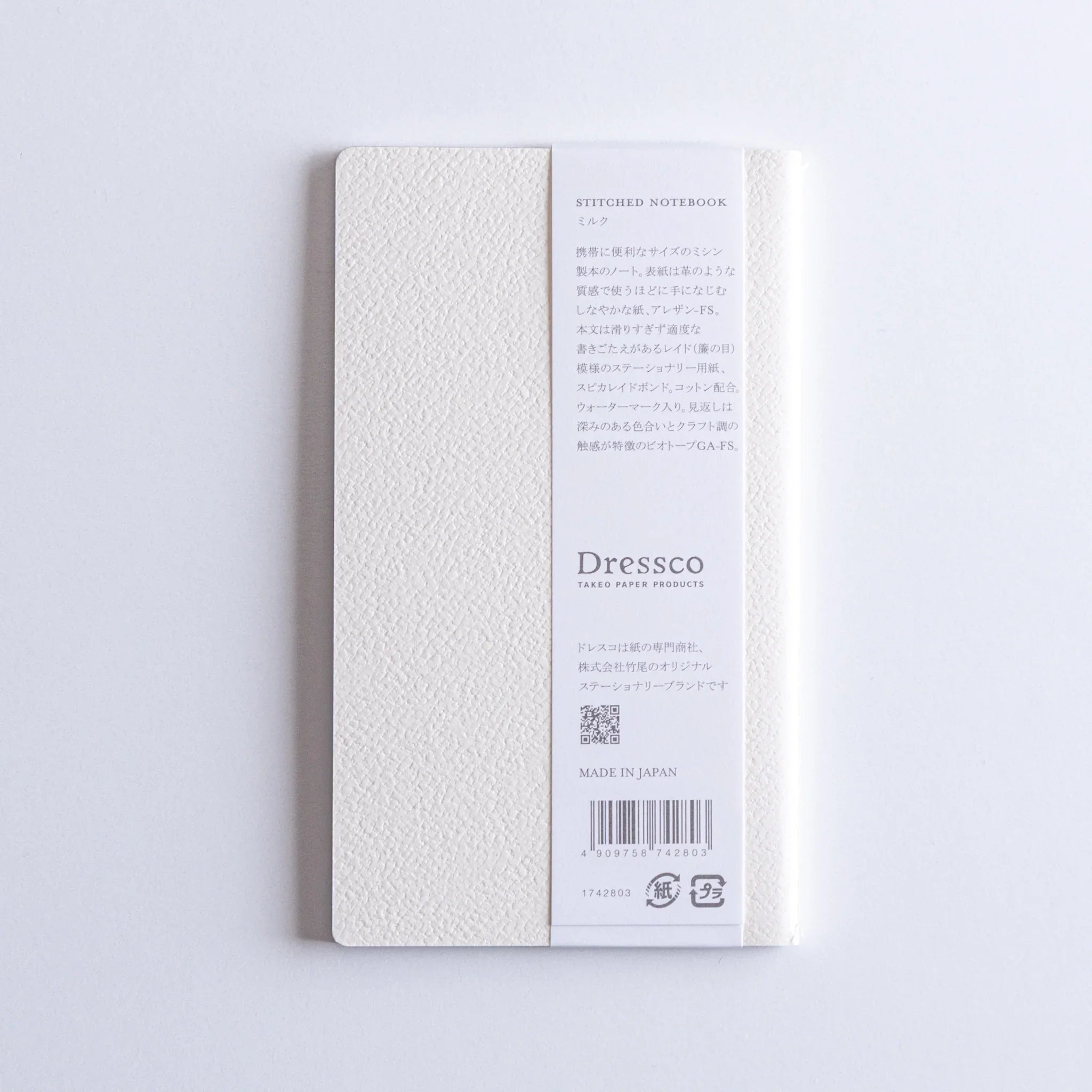 Spine edge of Dressco Spica Laid Bond Stitched A6 notebook showing the sewn binding and paper page stack visible