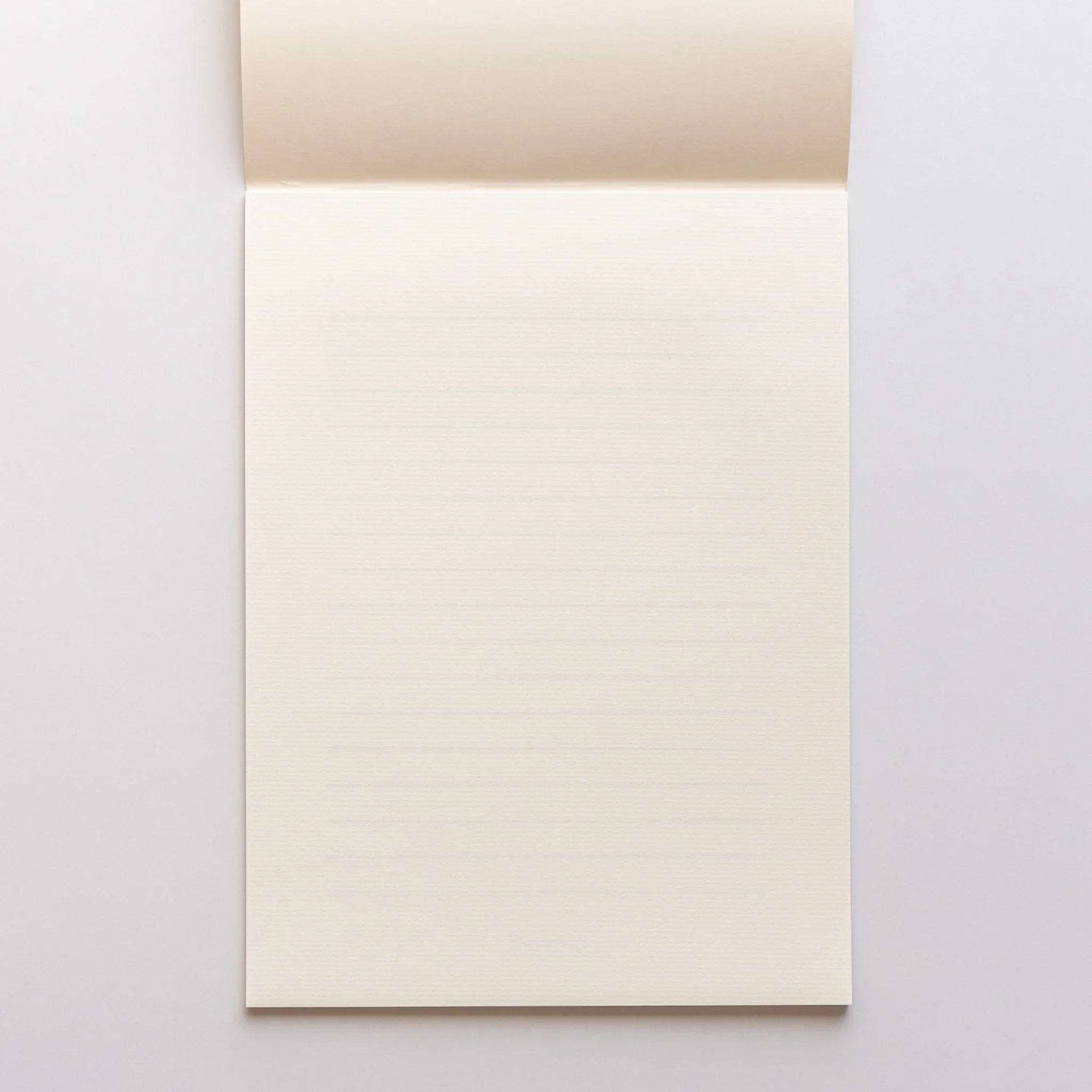 Strathmore writing pad opened flat showing blank cream colored pages with laid paper texture throughout