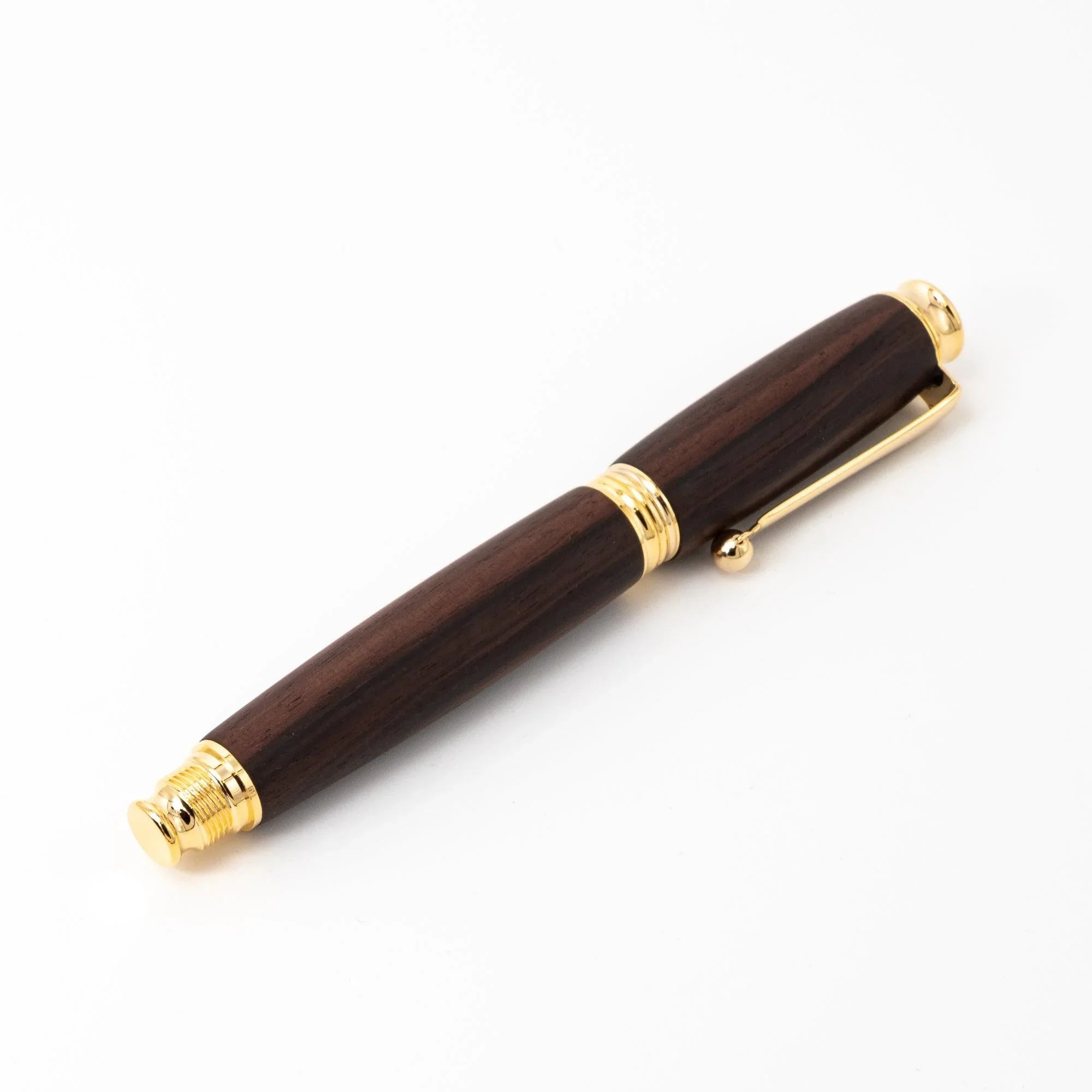 Fountain pen displayed overhead with metal cap removed on white writing surface and paper displayed clearly