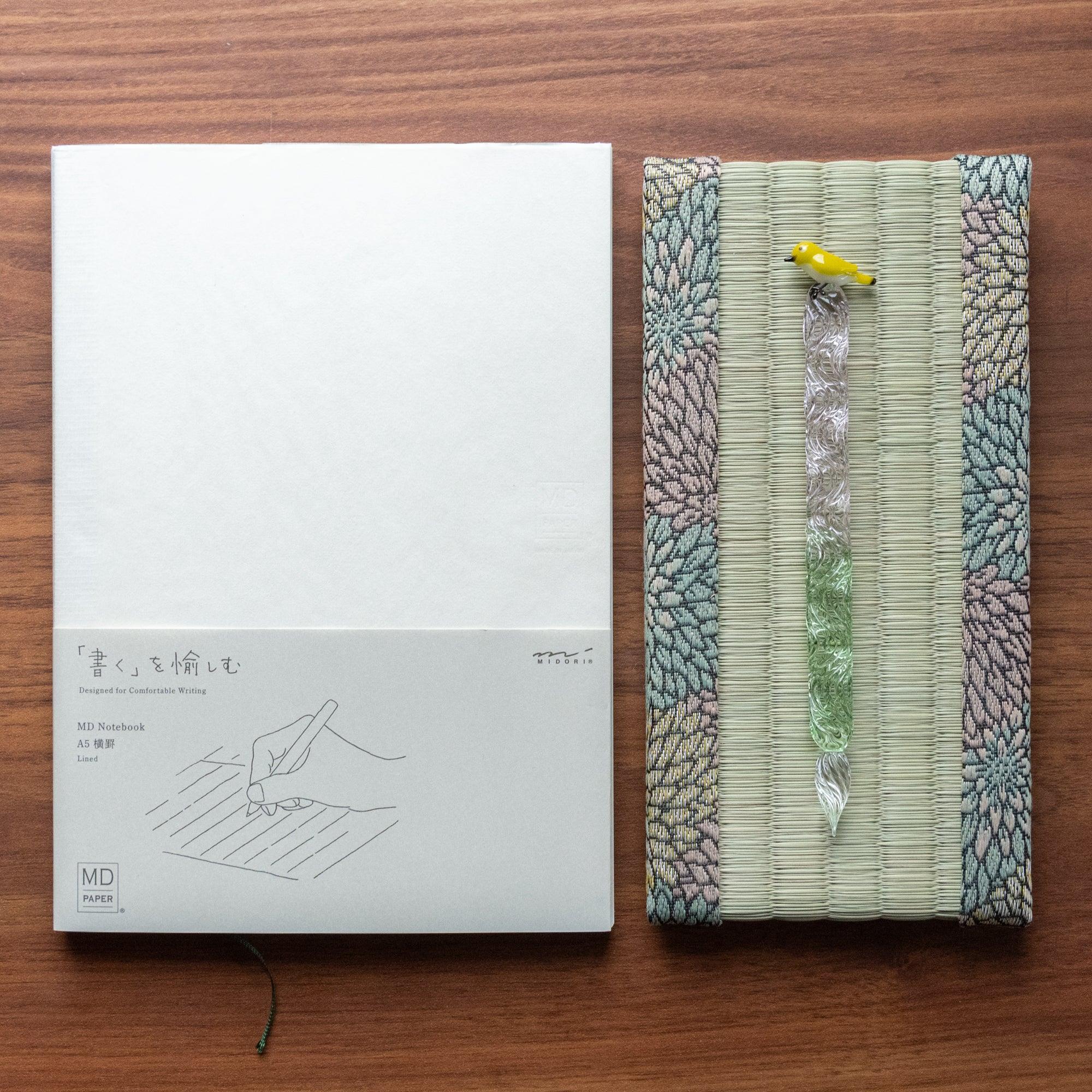 Chrysanthemum Tatami Pen Tray on walnut wood holding glass dip pen with yellow bird top next to Midori MD Notebook A5
