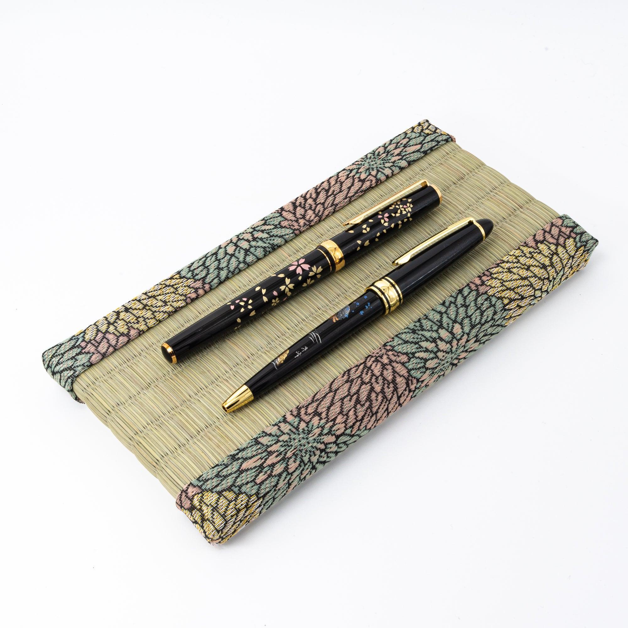 Chrysanthemum Tatami Pen Tray holding two black Japanese maki-e lacquer pens with gold accents on white background