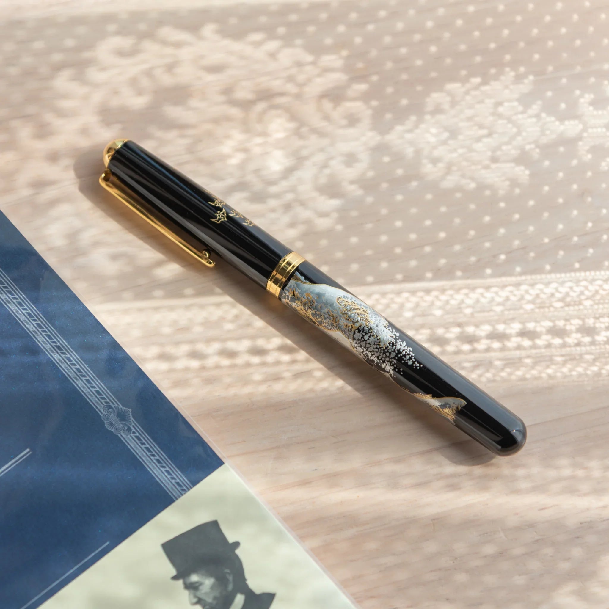 Traditional Yamanaka lacquered fountain pen depicts dramatic ocean wave and snow-capped mountain for writing