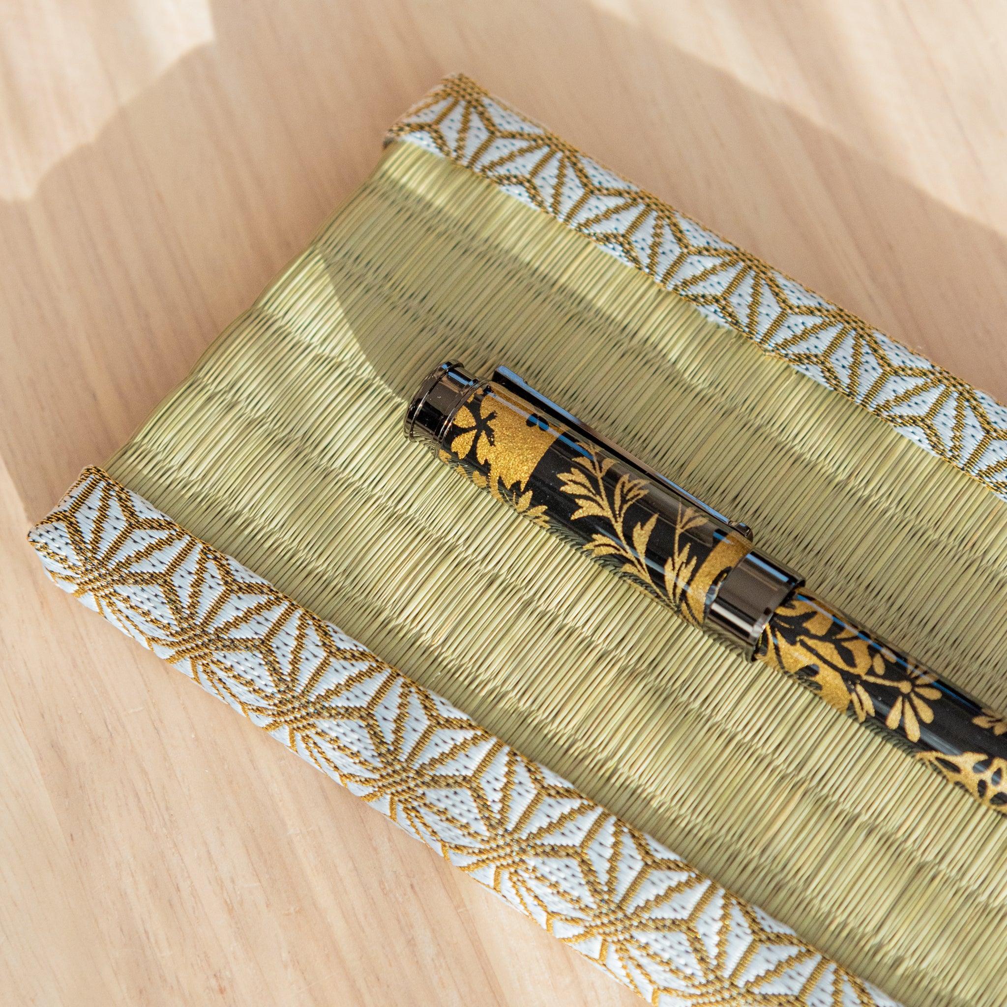 Styled product shot of hemp leaves tatami pen tray with pen positioned on woven mat surface for display in frame