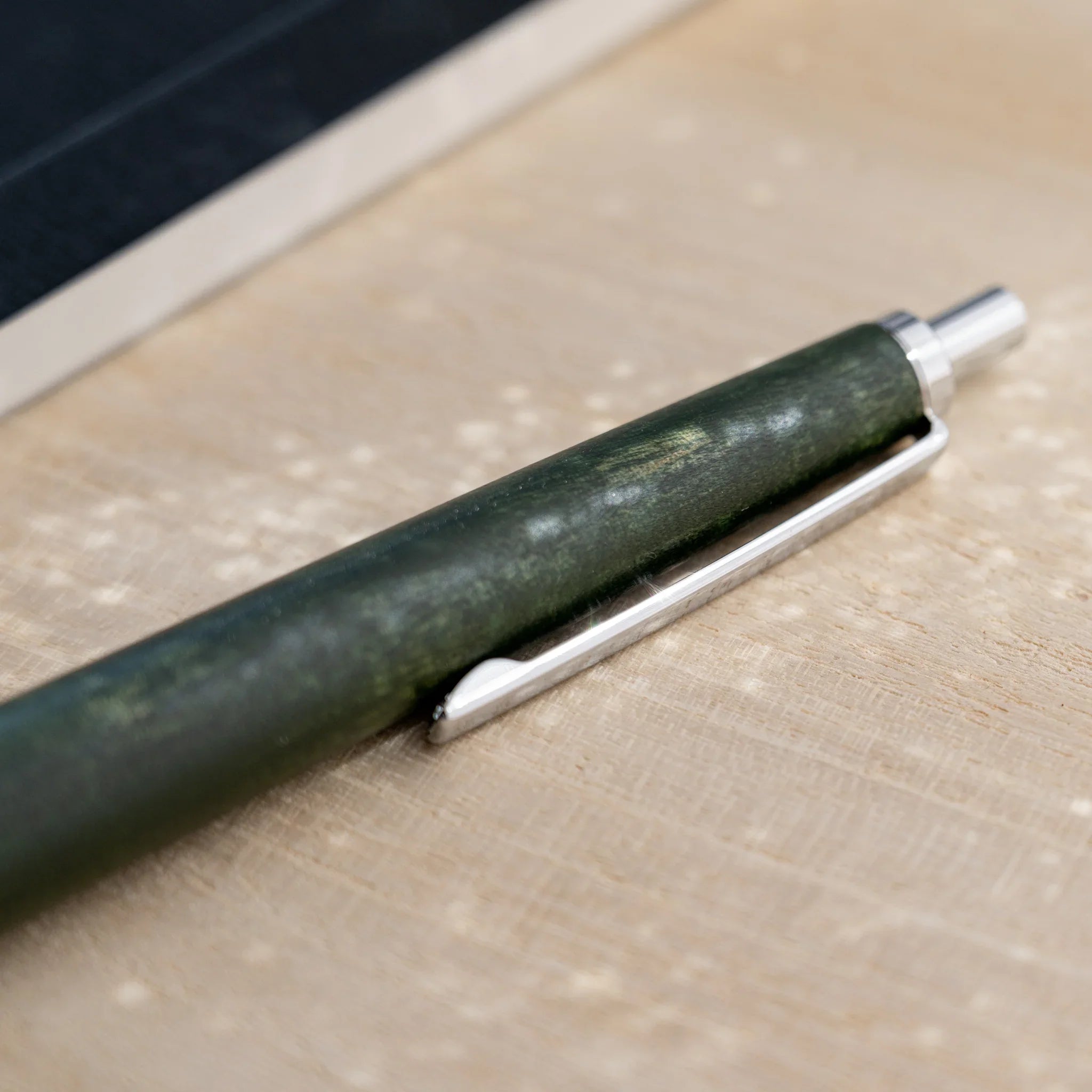 Olive green horse chestnut wood urushi ballpoint pen, close-up of barrel wood grain and silver clip, Japanese wood