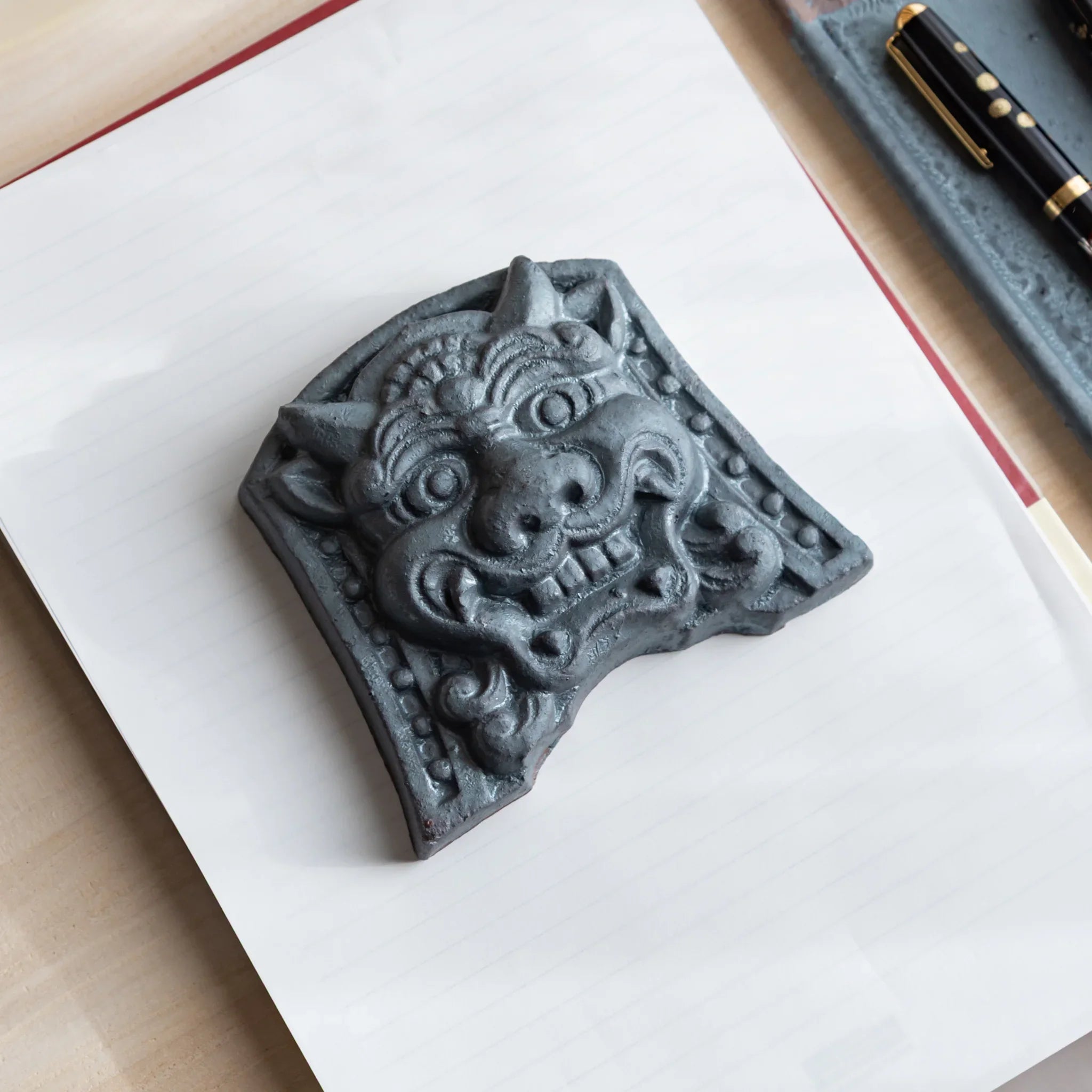 Japanese Kawara large roof guardian ceramic paperweight with resolute expression shown in detail view composition
