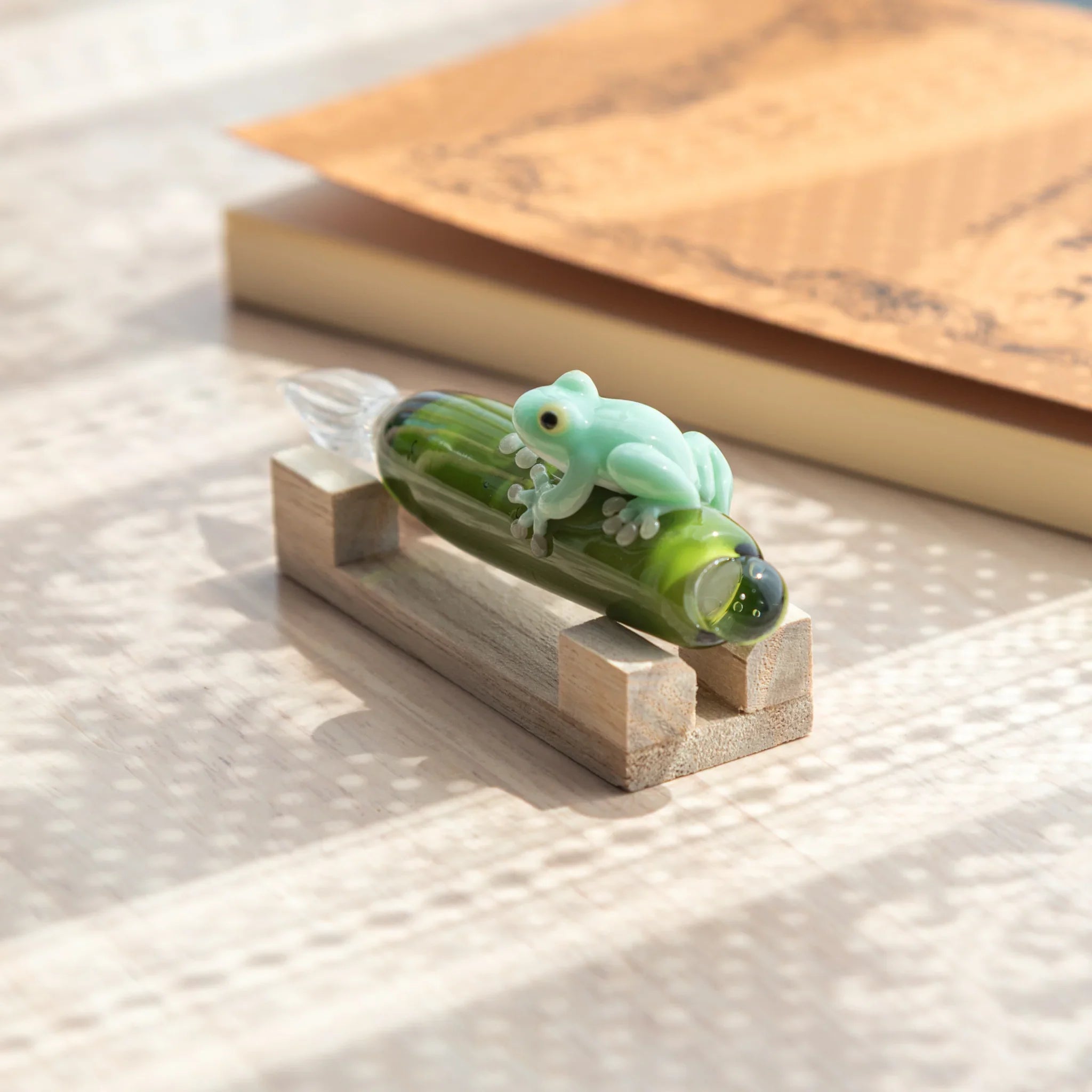 Glass dip pen with charming frog perched on lime green bottle and textured ceramic sand base holder with handle detail and