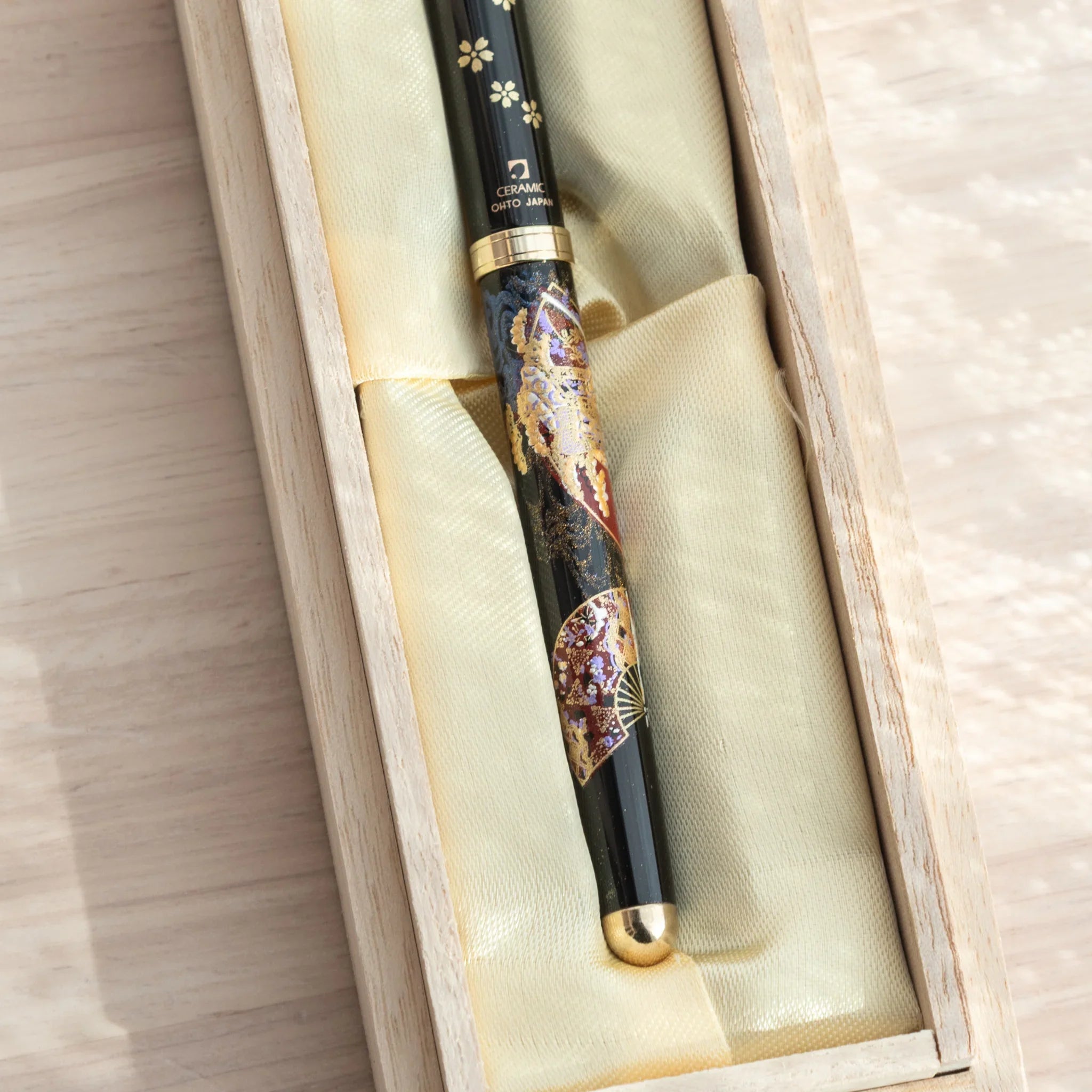 Yamanaka Japanese ballpoint pen in paulownia gift box, close-up showing OHTO JAPAN label, gold ring, and maki-e motifs