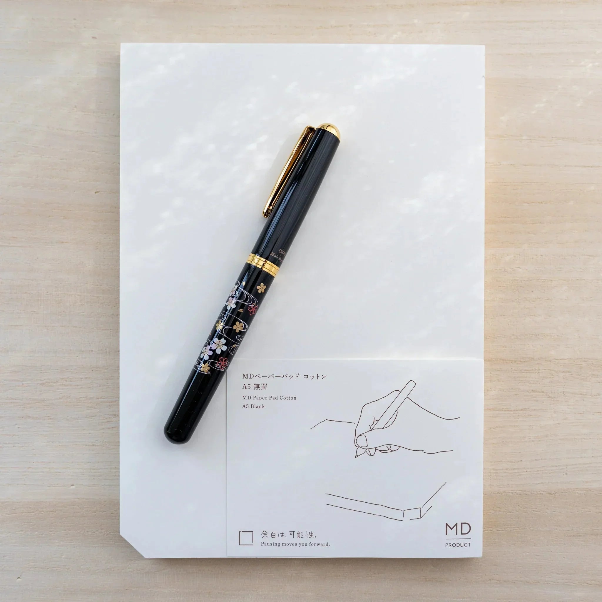 Midori MD Paper Pad Cotton A5 with brown belly band and a black gold-floral Japanese fountain pen resting on top