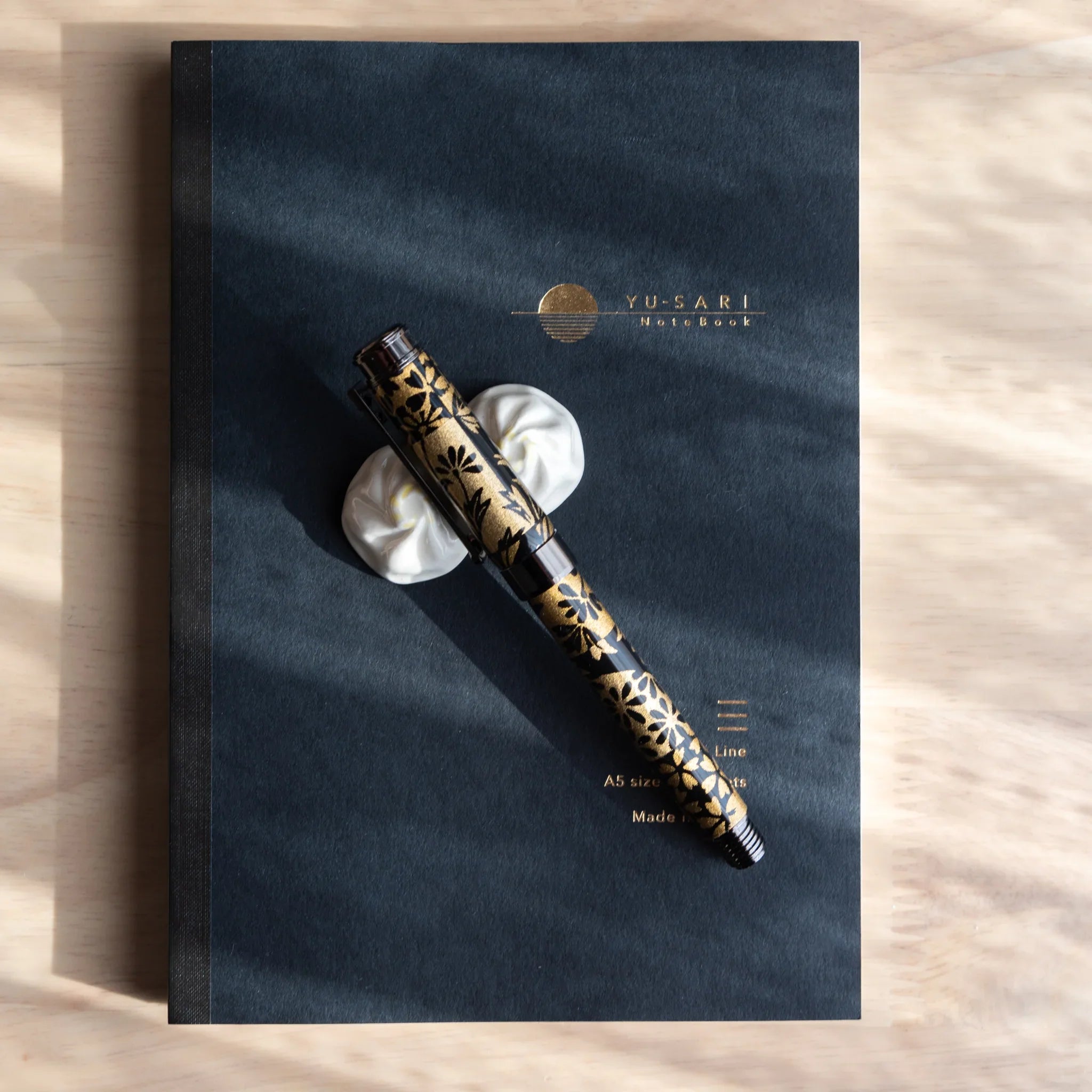 Uncapped fountain pen with black body and gold botanical Mino washi wrapper, silver metallic band and details nib