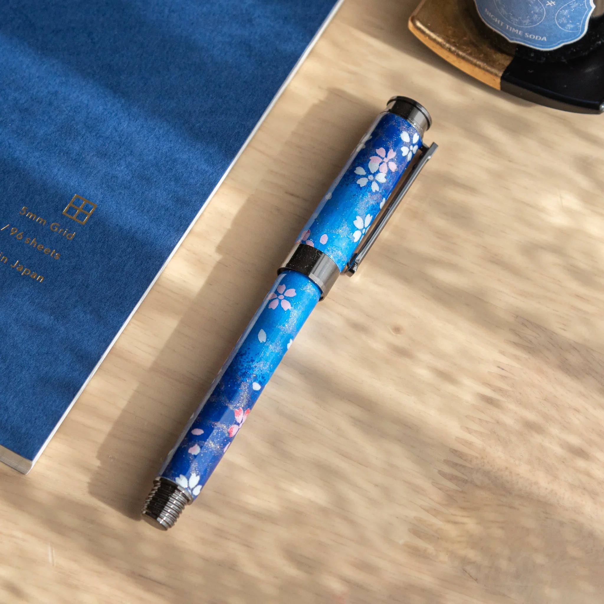 TACCIA Moonlit Sakura fountain pen with navy Mino washi wrapper featuring white and pink cherry blossoms, front angled view