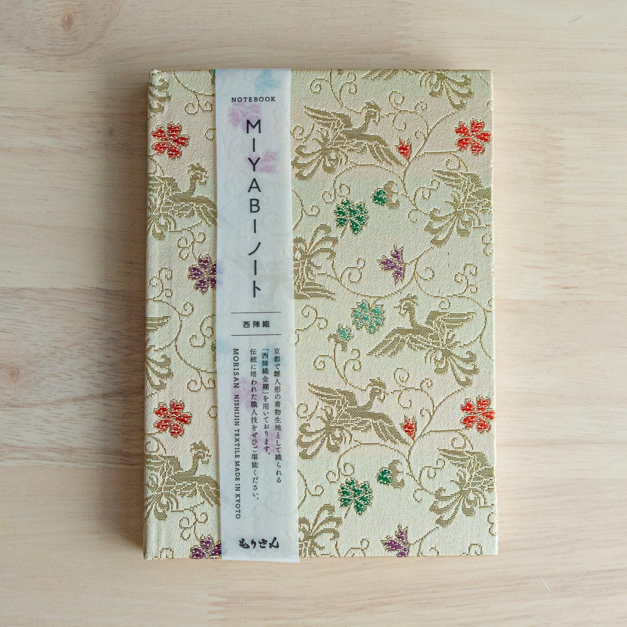 Nishijin textile Japanese notebook with pale gold phoenix cover and pink belly band reading MIYABI Notebook MORISAN KYOTO