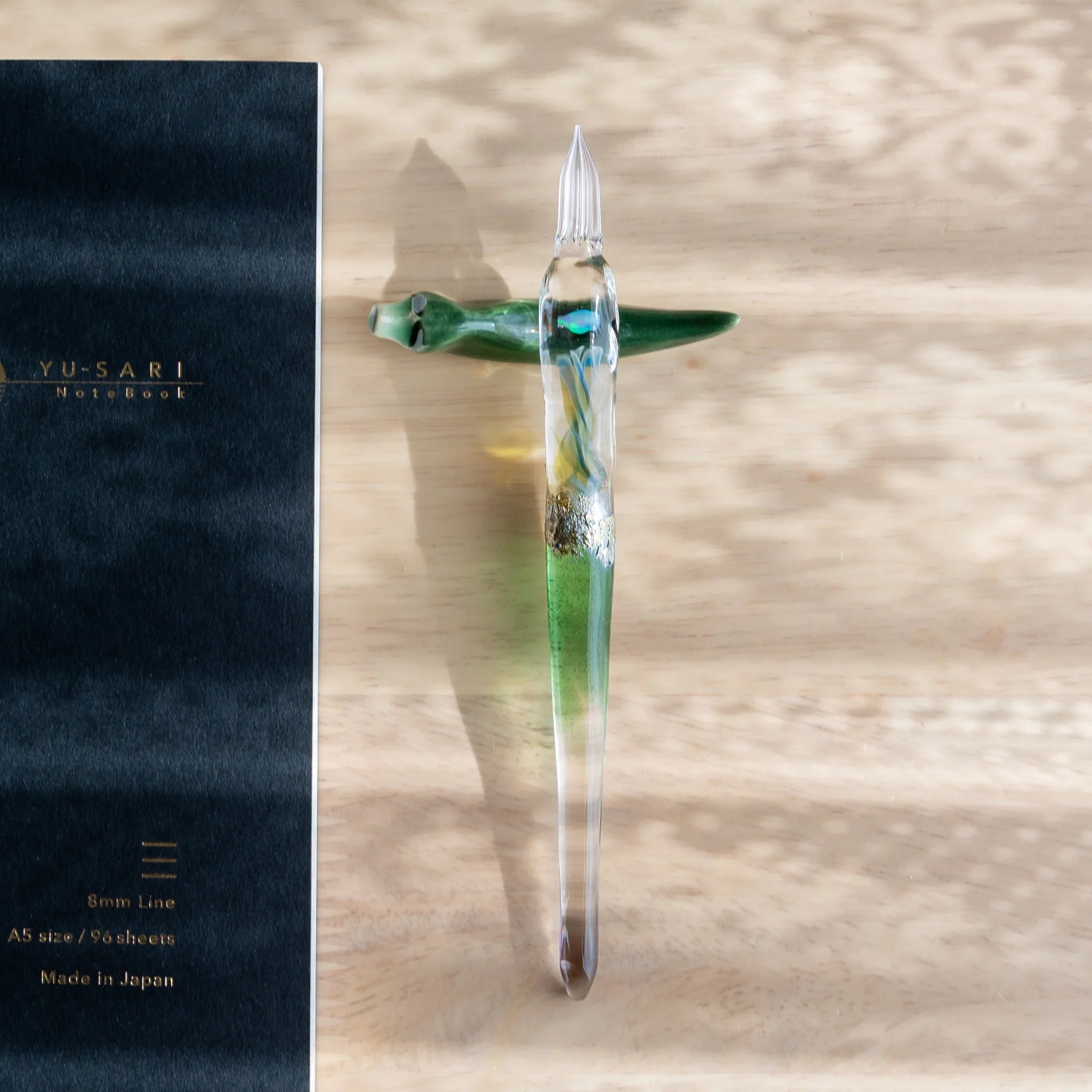 Dark lacquered fountain pen with intricate gold botanical design on indigo Mino washi patterned background angle