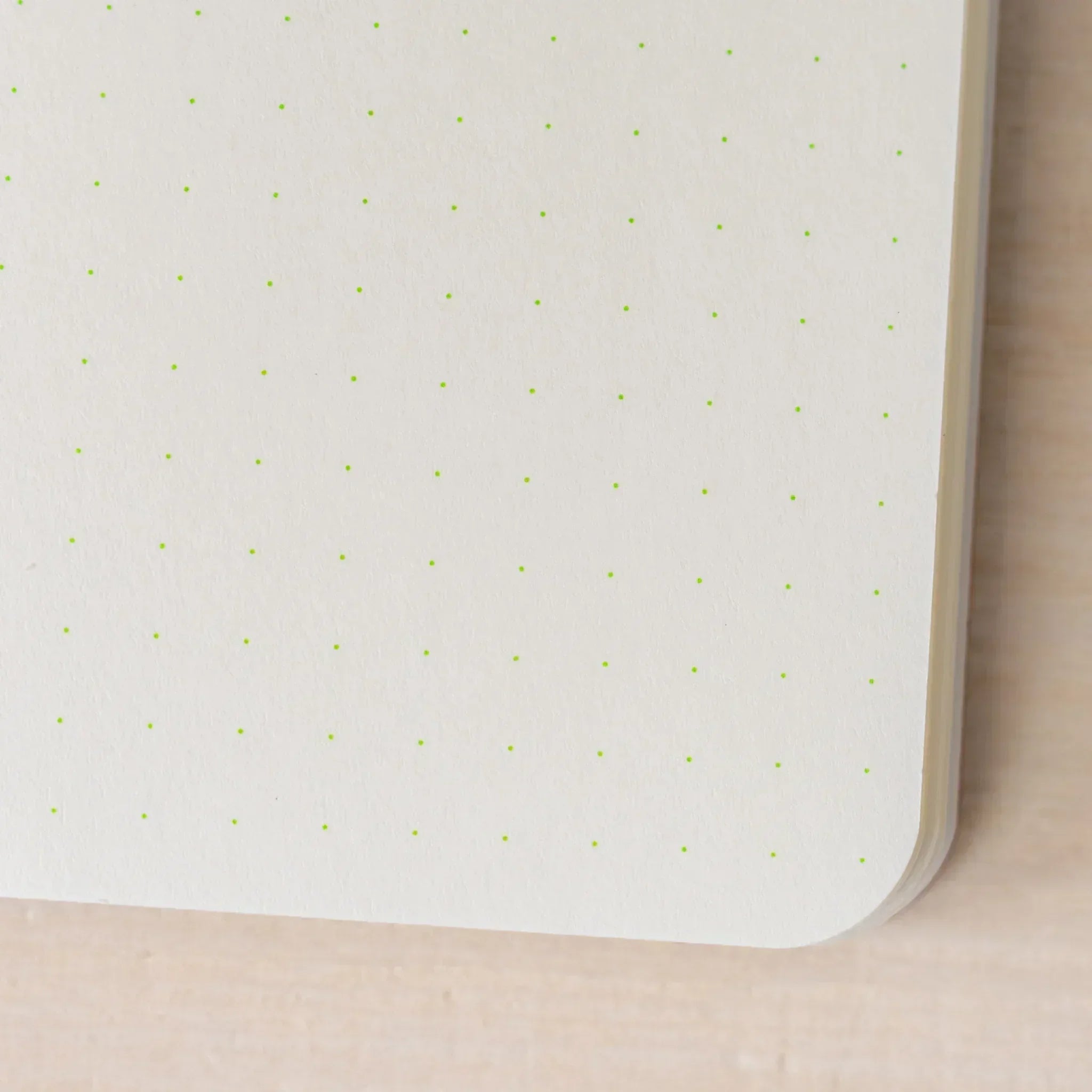 Close-up of RO-BIKI NOTE ivory page showing green dots in a grid pattern, rounded corner and page edges visible