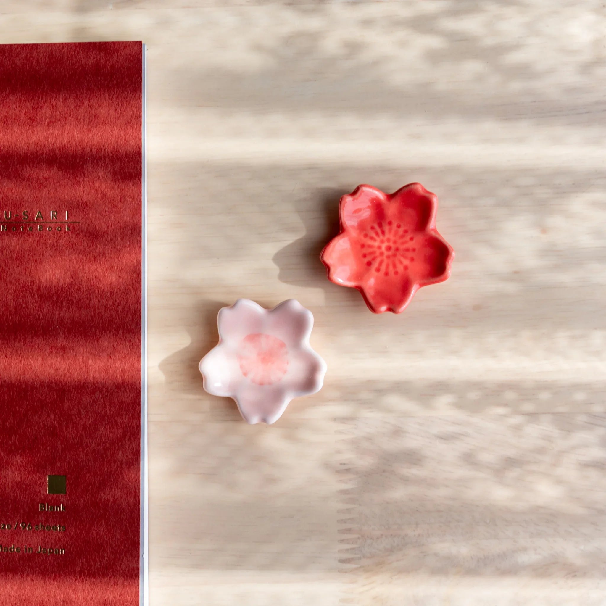Pale pink handcrafted sakura pen rest featuring detailed petal ridges and polished grooved interior pen on neutral surface