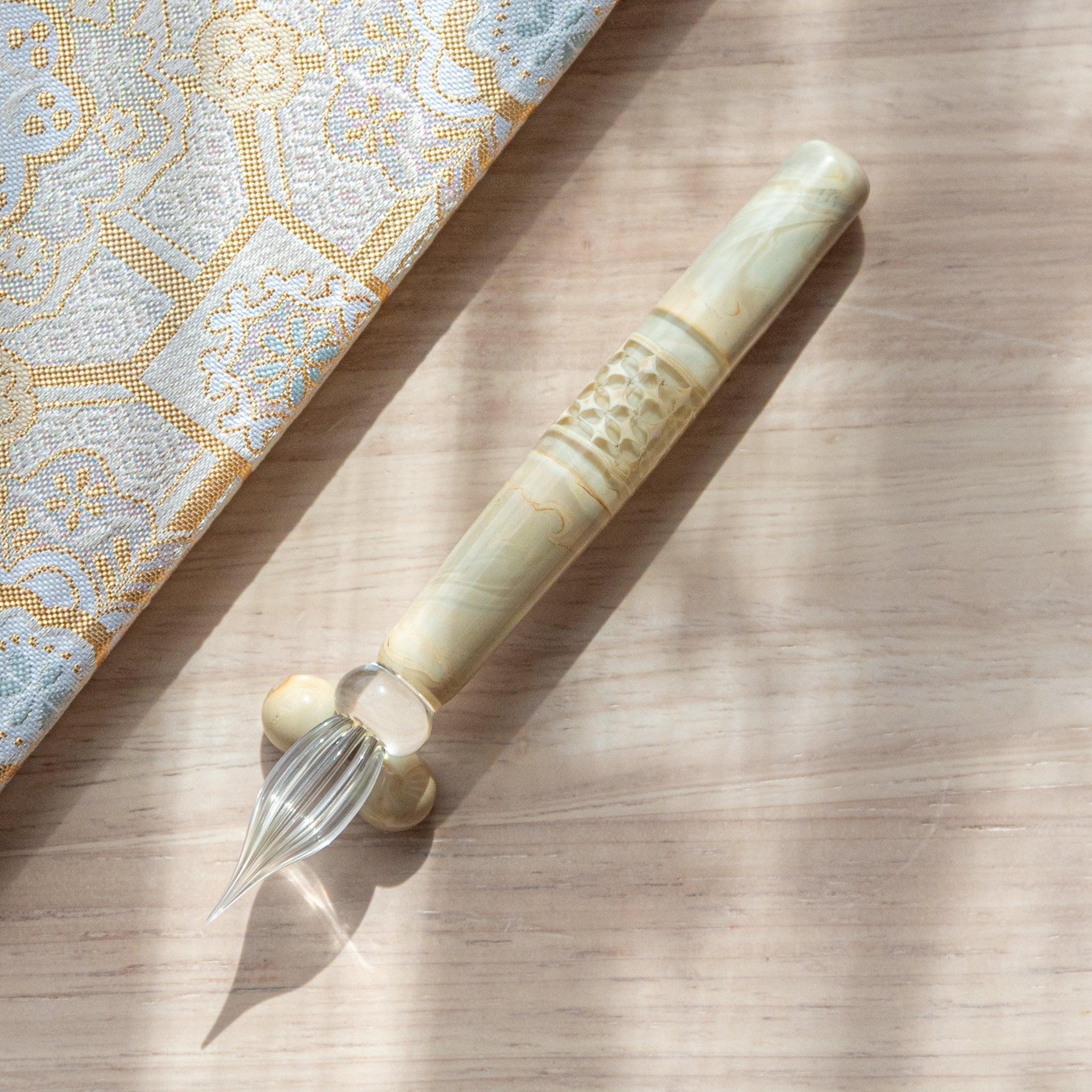 Shippo patterned wooden dip pen with engraved geometric cloisonne-style design and glass nib on fabric in frame