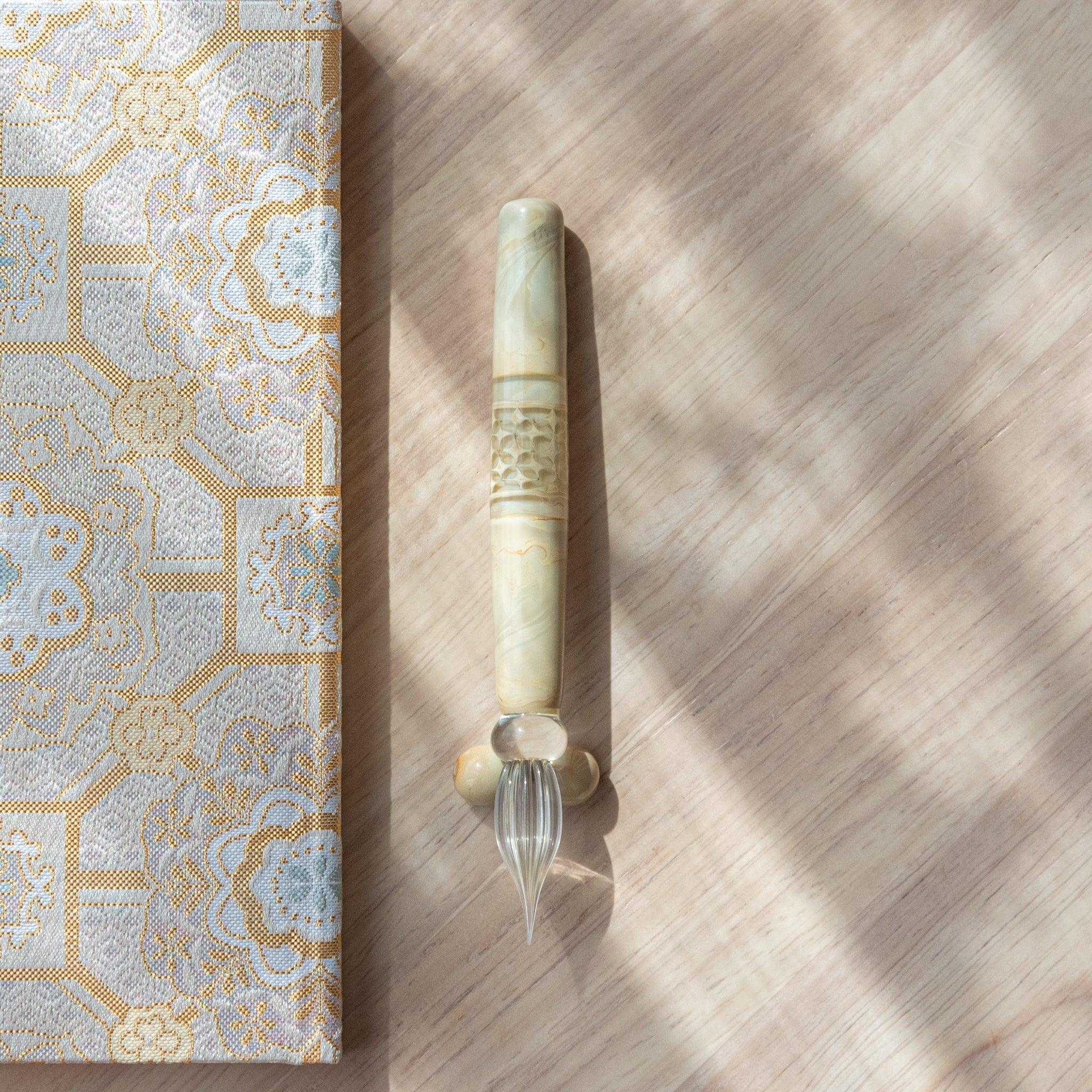 Detailed view of shippo wooden dip pen showing natural grain, engraved pattern detail, and glass nib visible overall