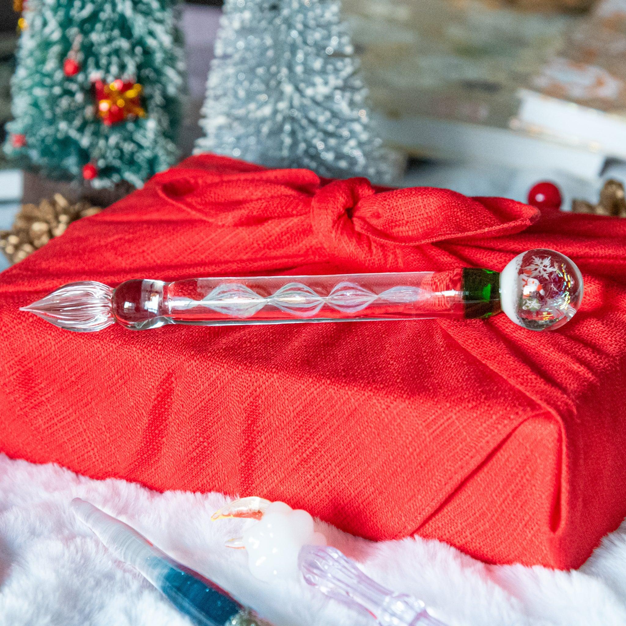Clear glass dip pen with delicately twisted stem and miniature winter snow globe scene at transparent barrel end