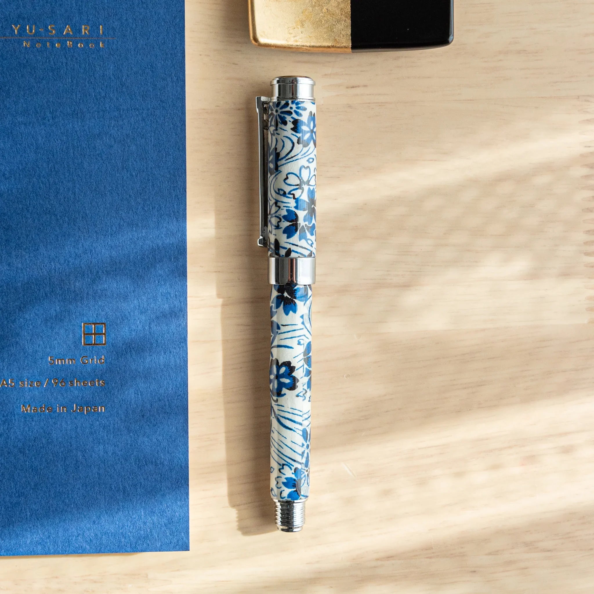 Japanese fountain pen with navy blue Mino washi featuring white and dark blue flowing cherry blossoms angled view