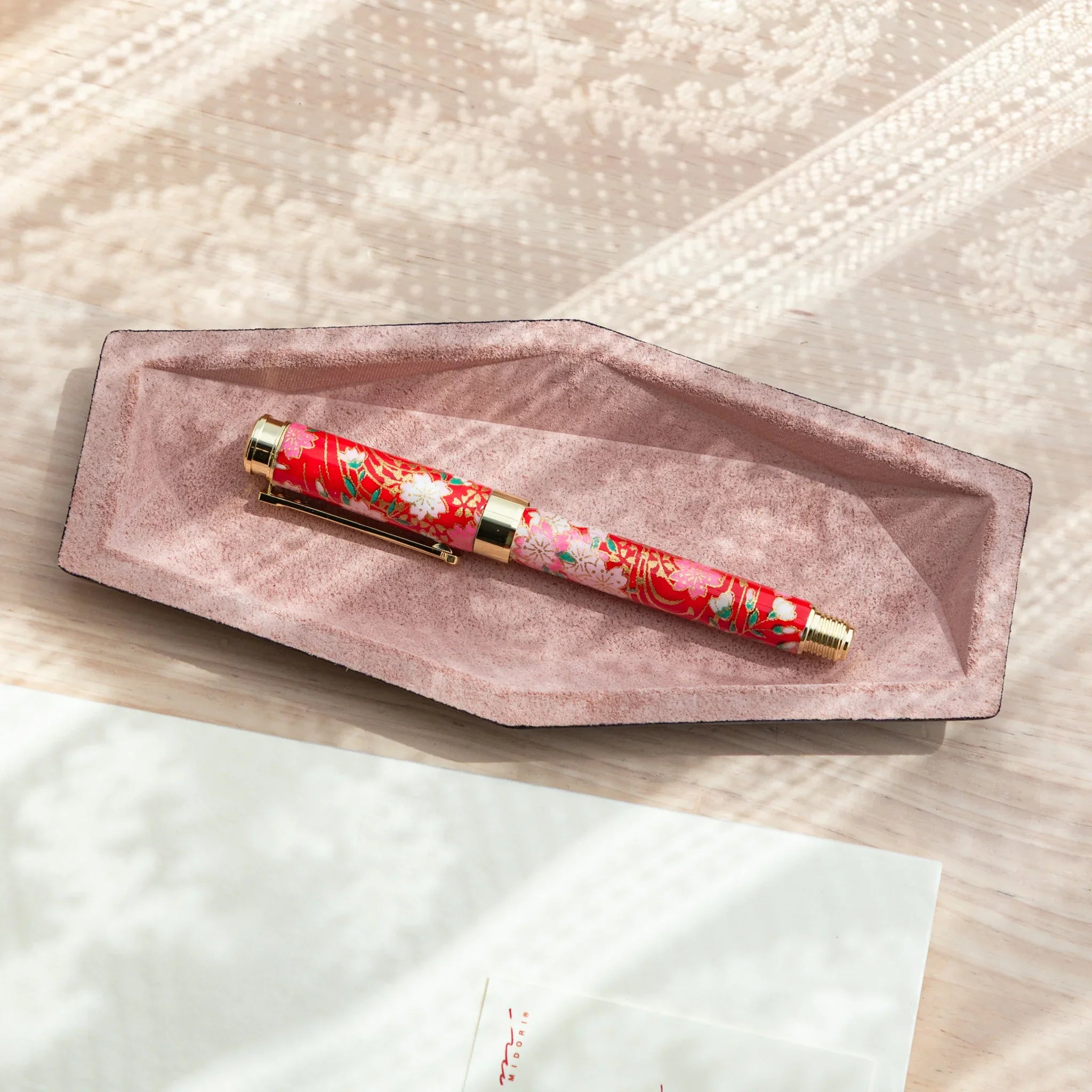Pink suede hexagonal slim pen tray from above holding a Japanese floral fountain pen in red and pink with gold trim
