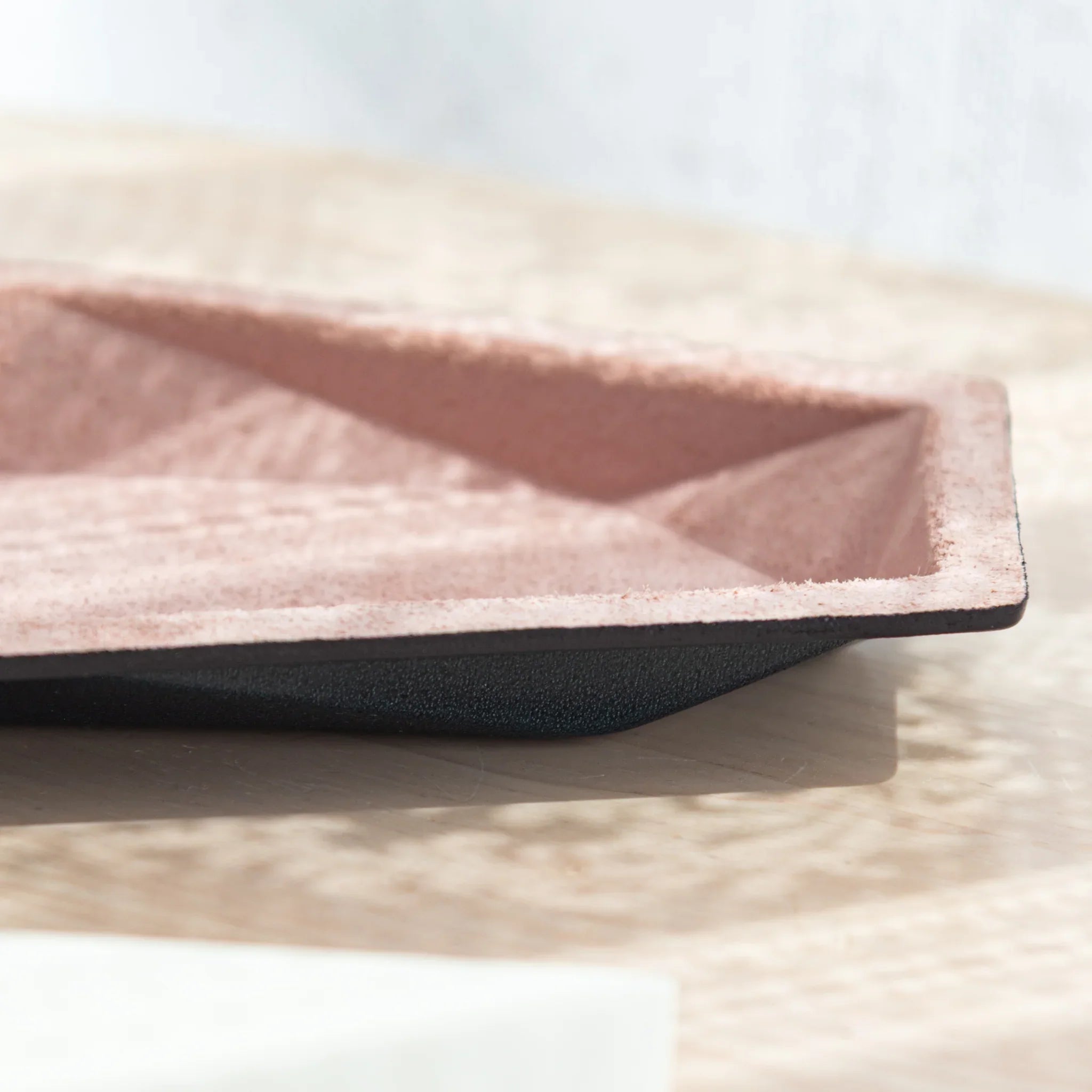 Side-angle profile of pink suede hexagonal slim pen tray showing geometric interior walls and black leather exterior base