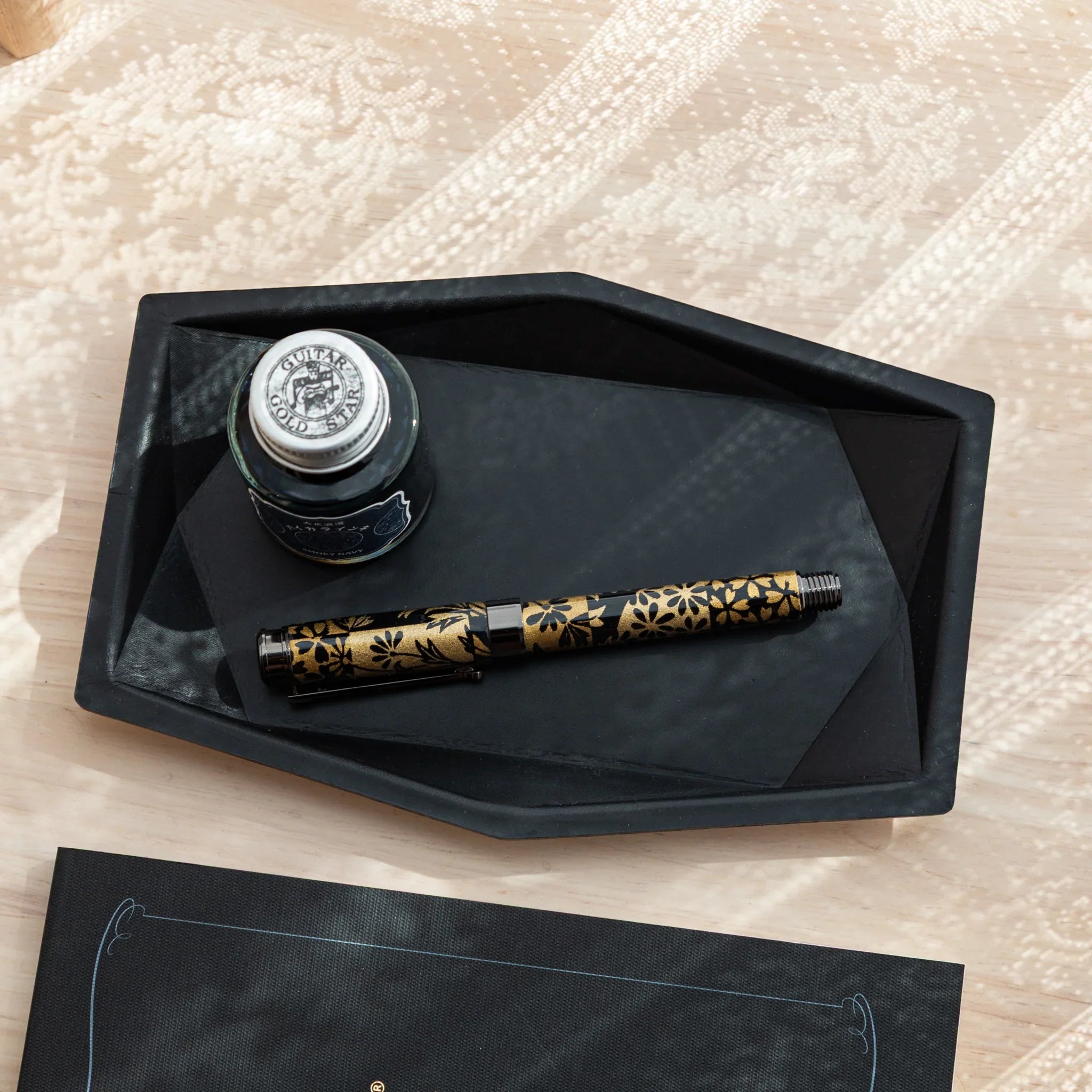Black hexagonal leather pen tray from above with single fountain pen displayed clearly in center storage space