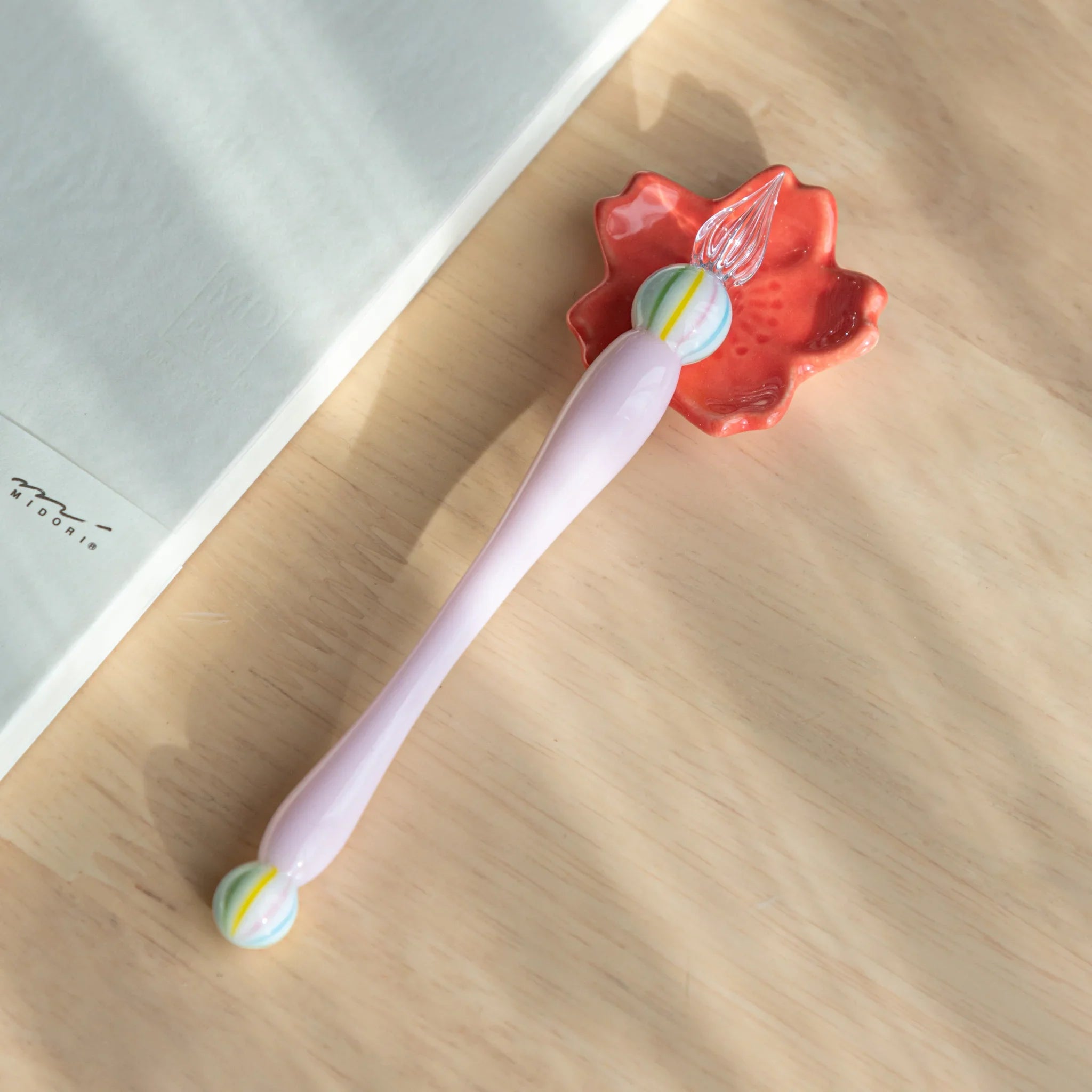 Wagashi Sakura Mochi glass dip pen held in hand displaying coral red mochi-shaped decorative top with pink shaft