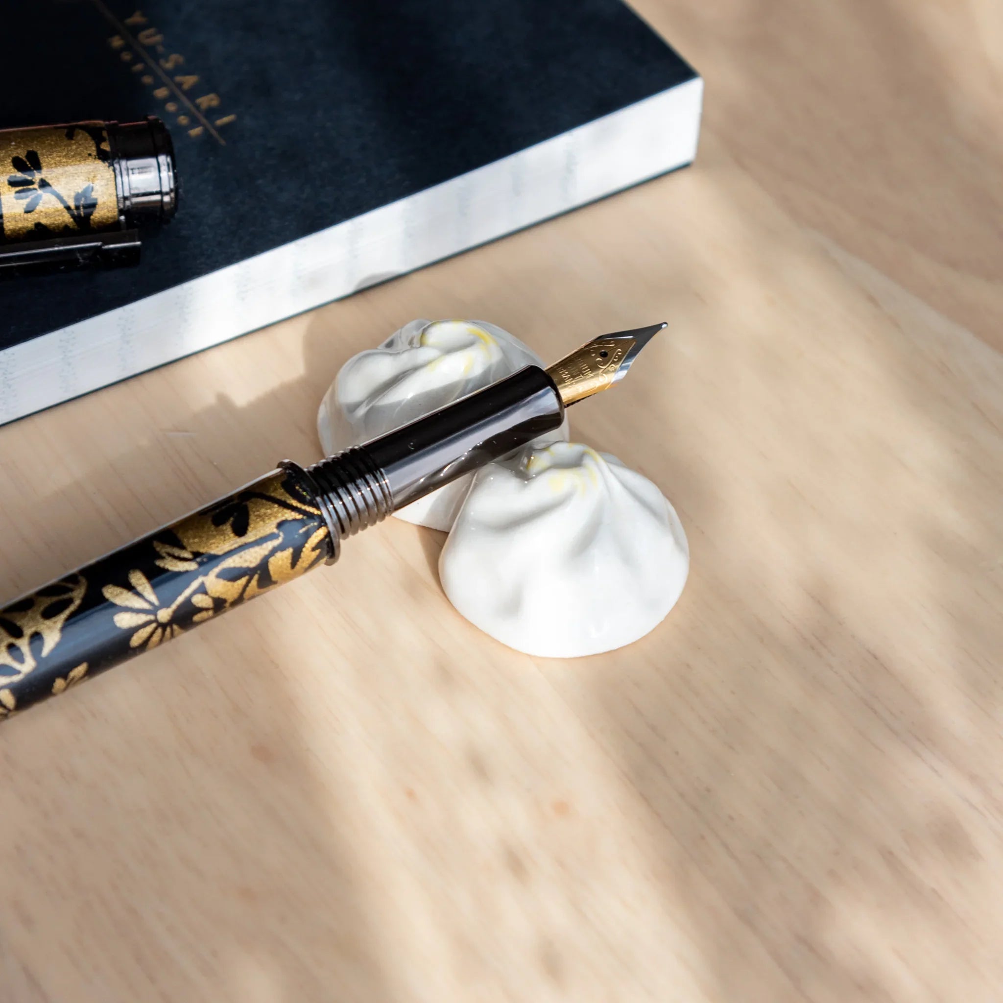 Xiaolongbao pen rest handcrafted white ceramic with authentic Japanese dumpling form and surface texture close shot