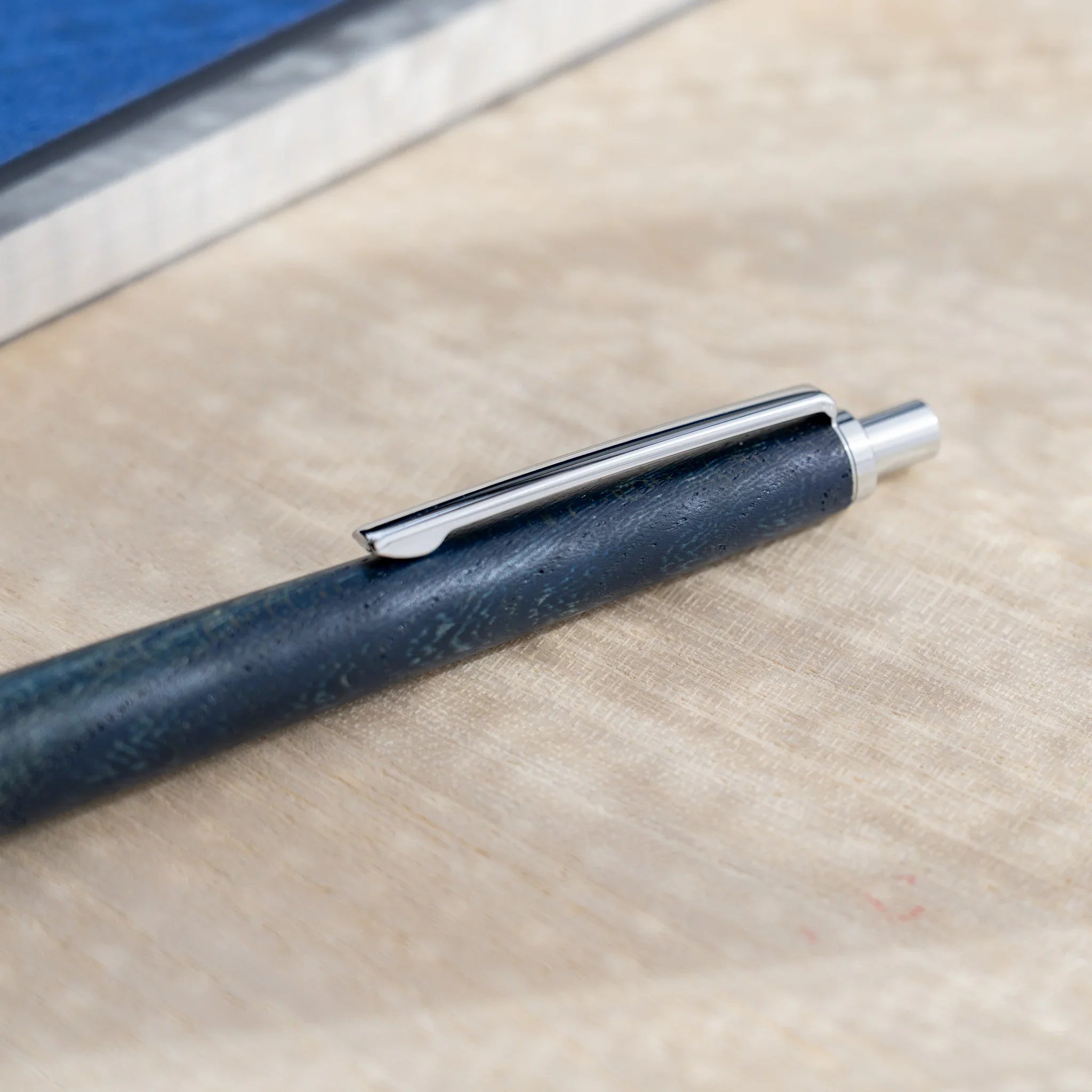 Indigo blue zelkova wood urushi mechanical pencil, close-up of barrel wood grain and silver clip, Japanese keyaki