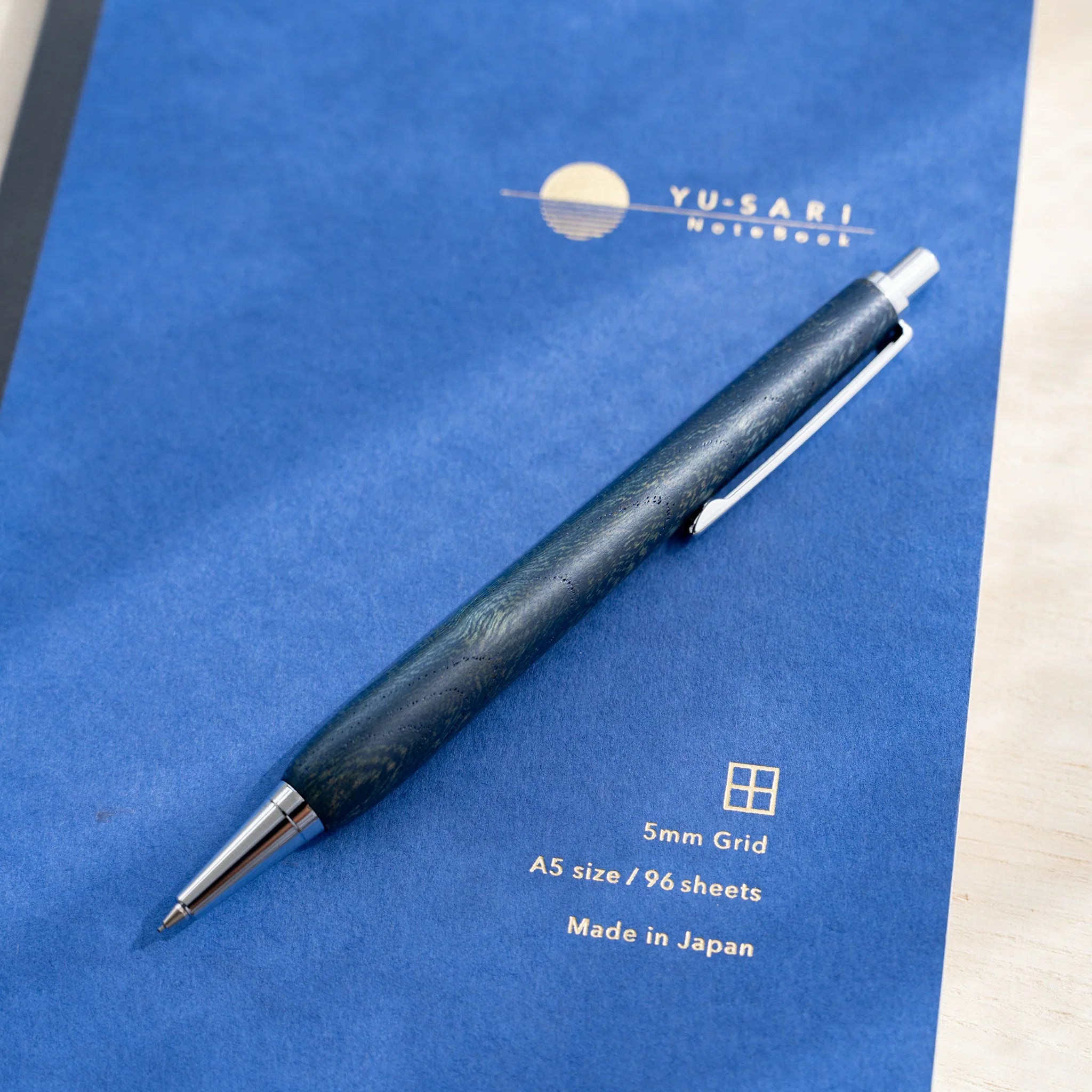 Zelkova wood urushi lacquered mechanical pencil in indigo blue on blue paper, Japanese keyaki wood