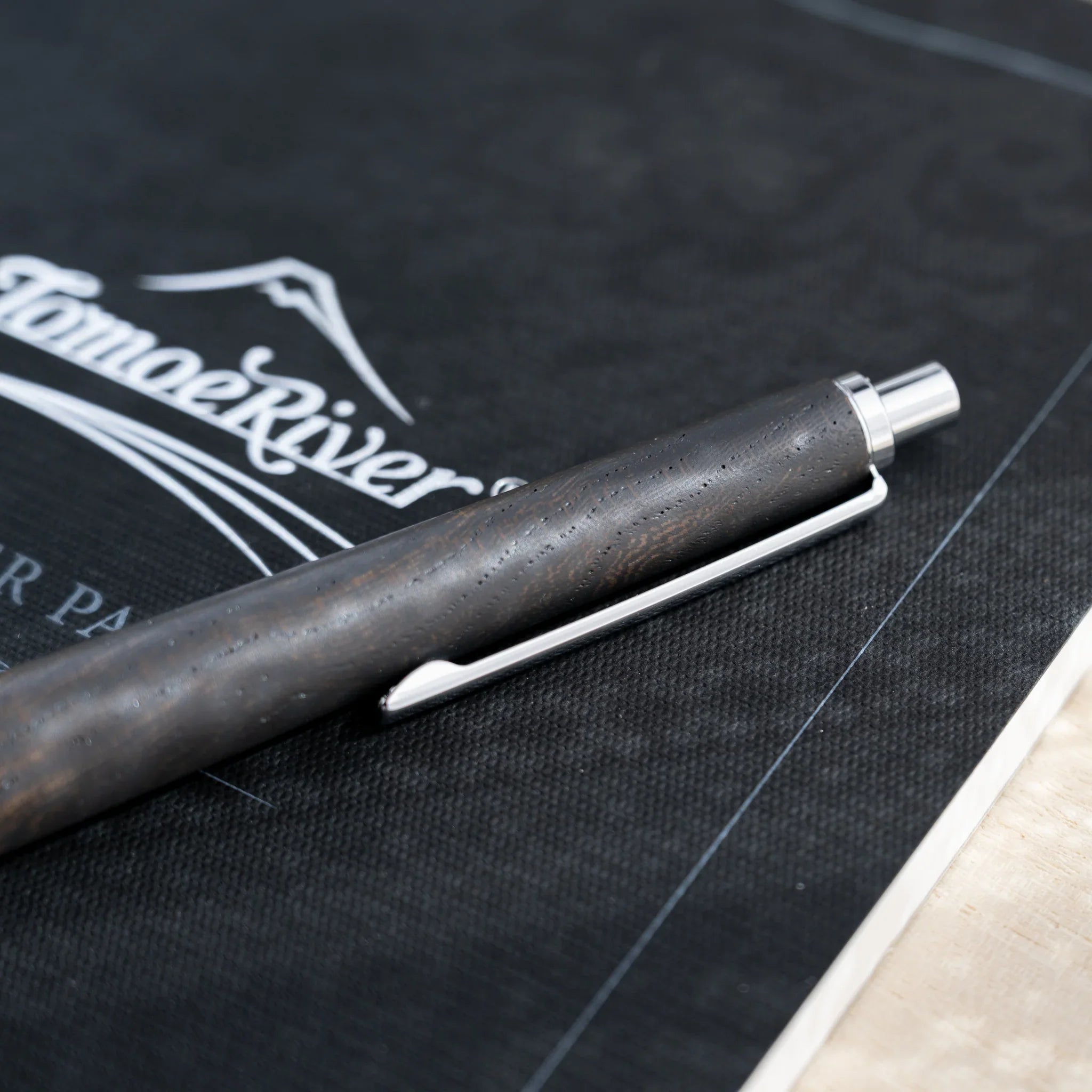 Charcoal black zelkova wood urushi mechanical pencil, close-up of knock end and silver clip, Japanese keyaki wood