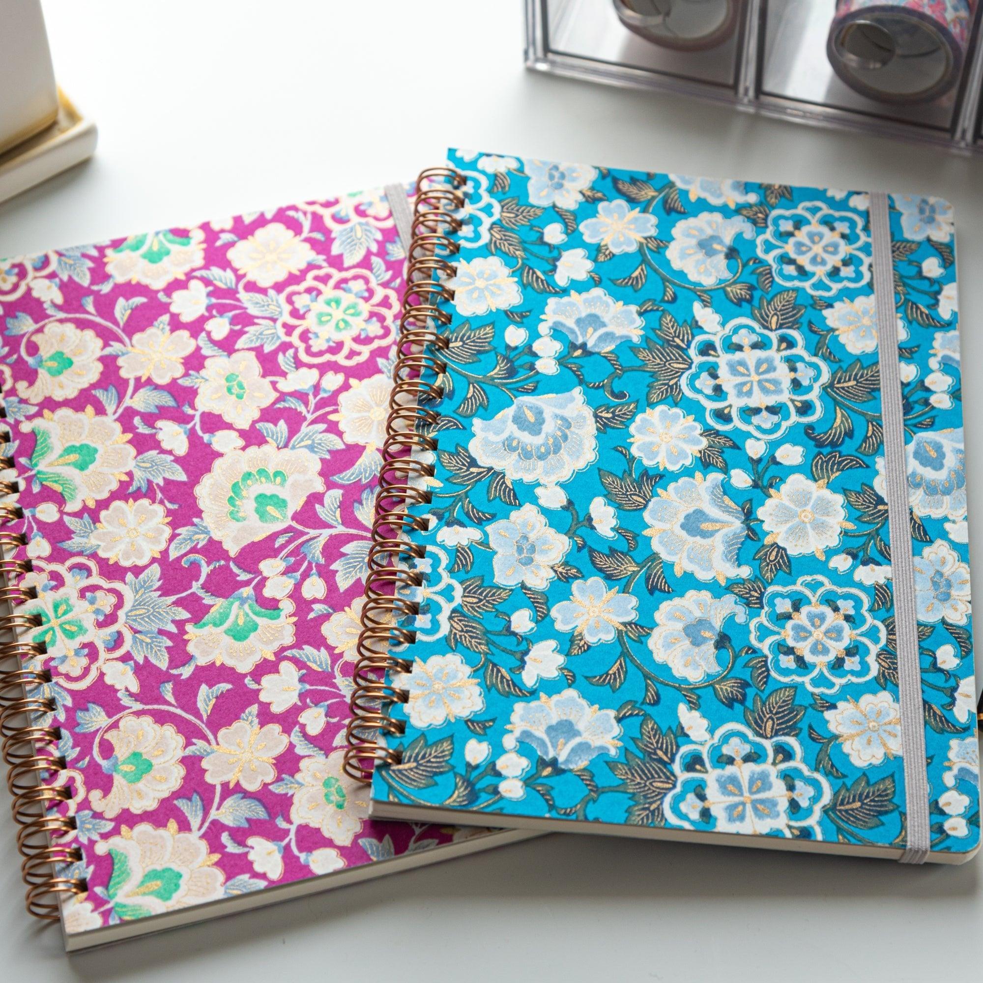 Spiral-bound notebook with blue garden washi cover unfolded showing interior blank pages for writing