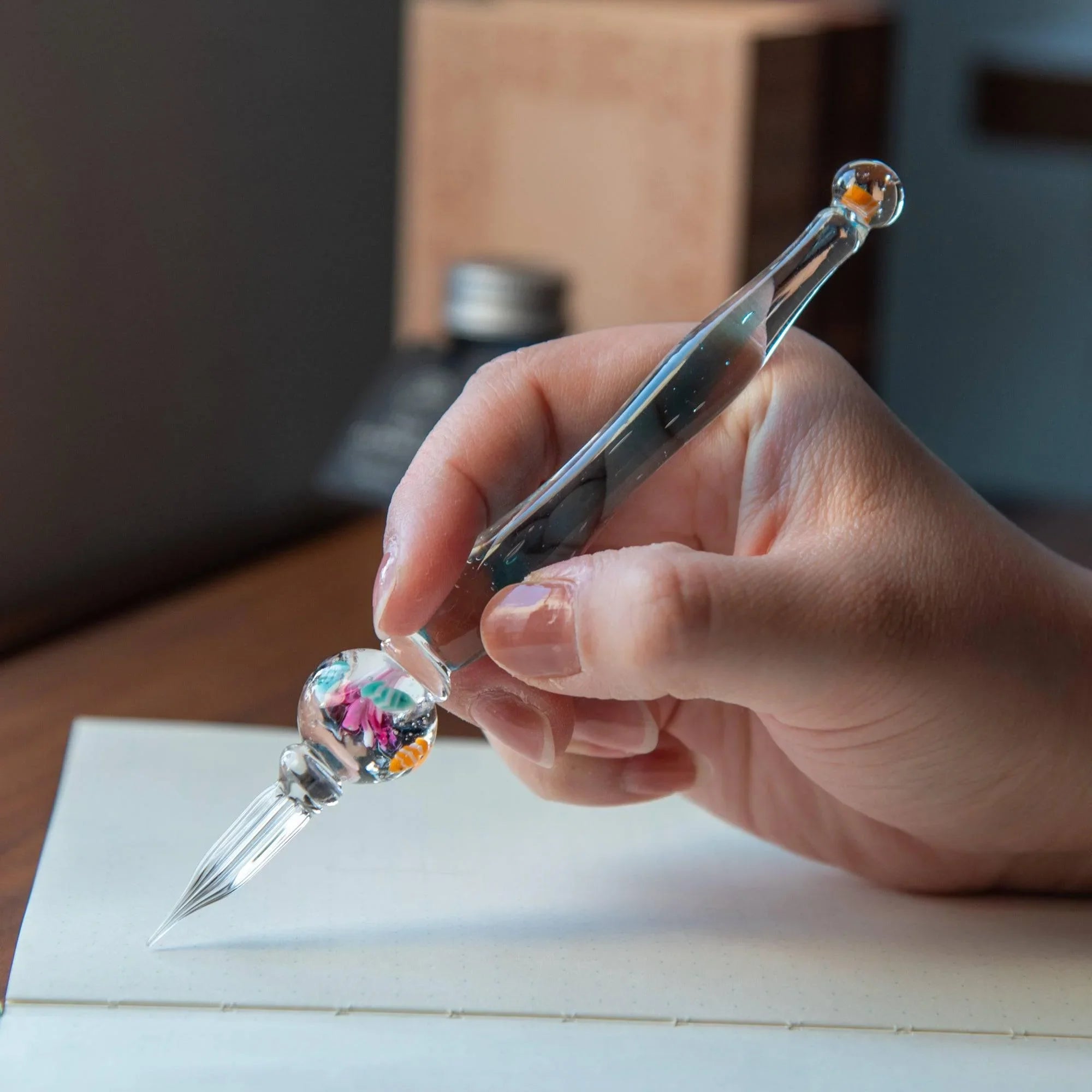 Japanese glass dip pen nib end close-up with orange-white striped clownfish visible in clear glass aquarium barrel