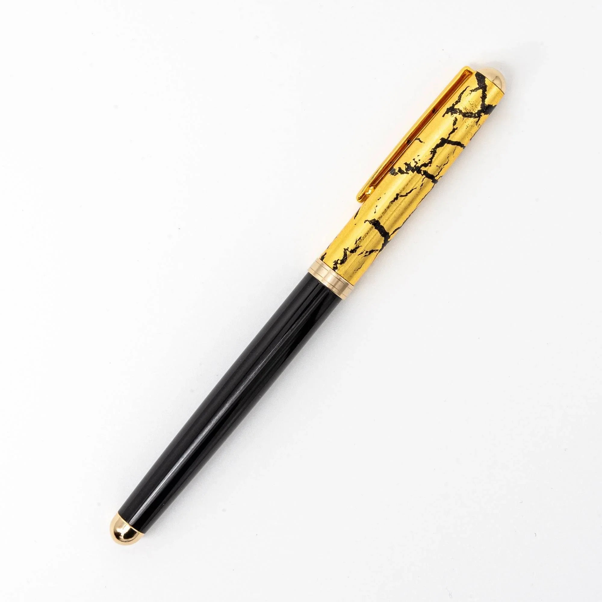 Japanese black ballpoint pen capped diagonal view showing gold crackle cap and gold band accents detail