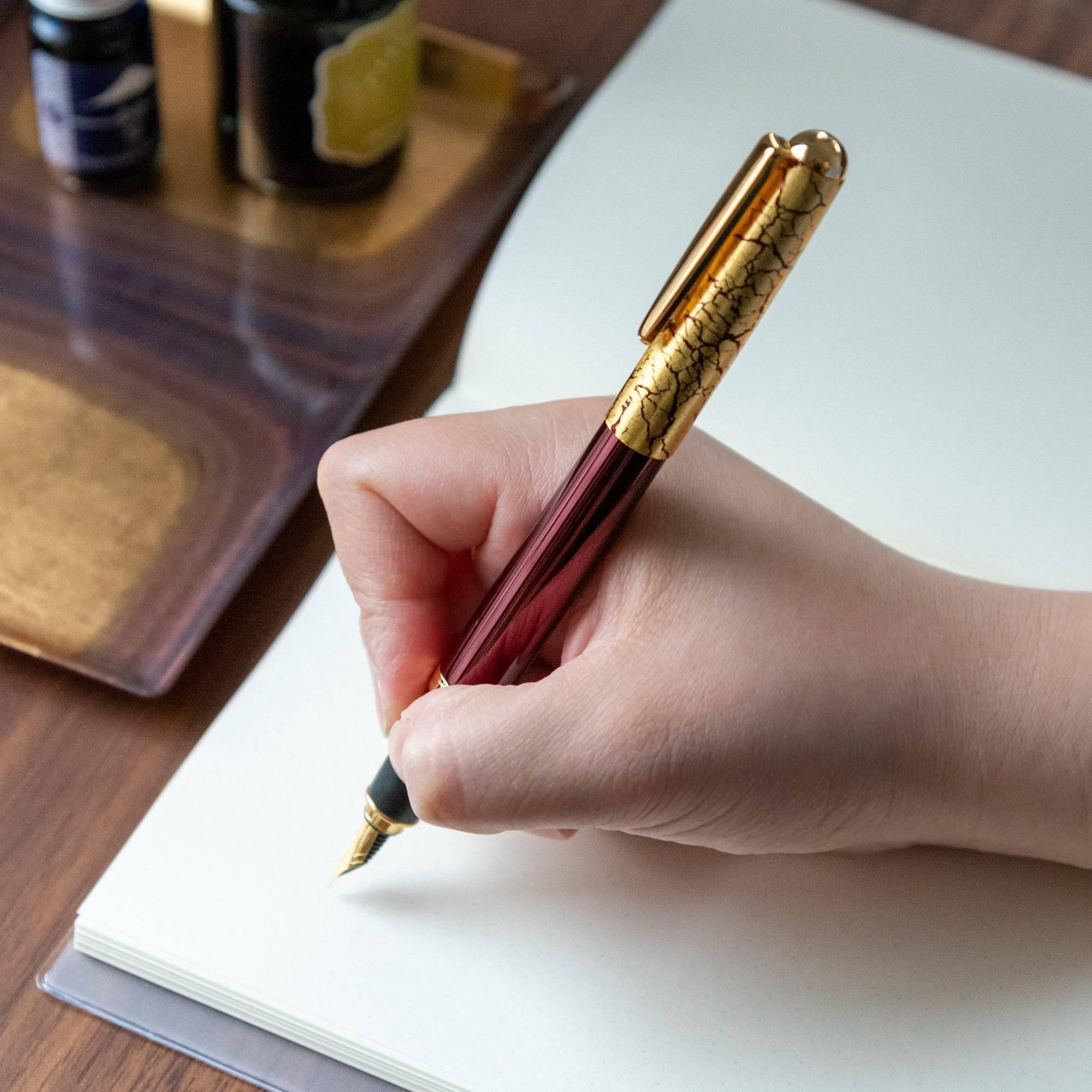 Wine red fountain pen uncapped revealing deep burgundy lacquer barrel with scattered gold crackle texture