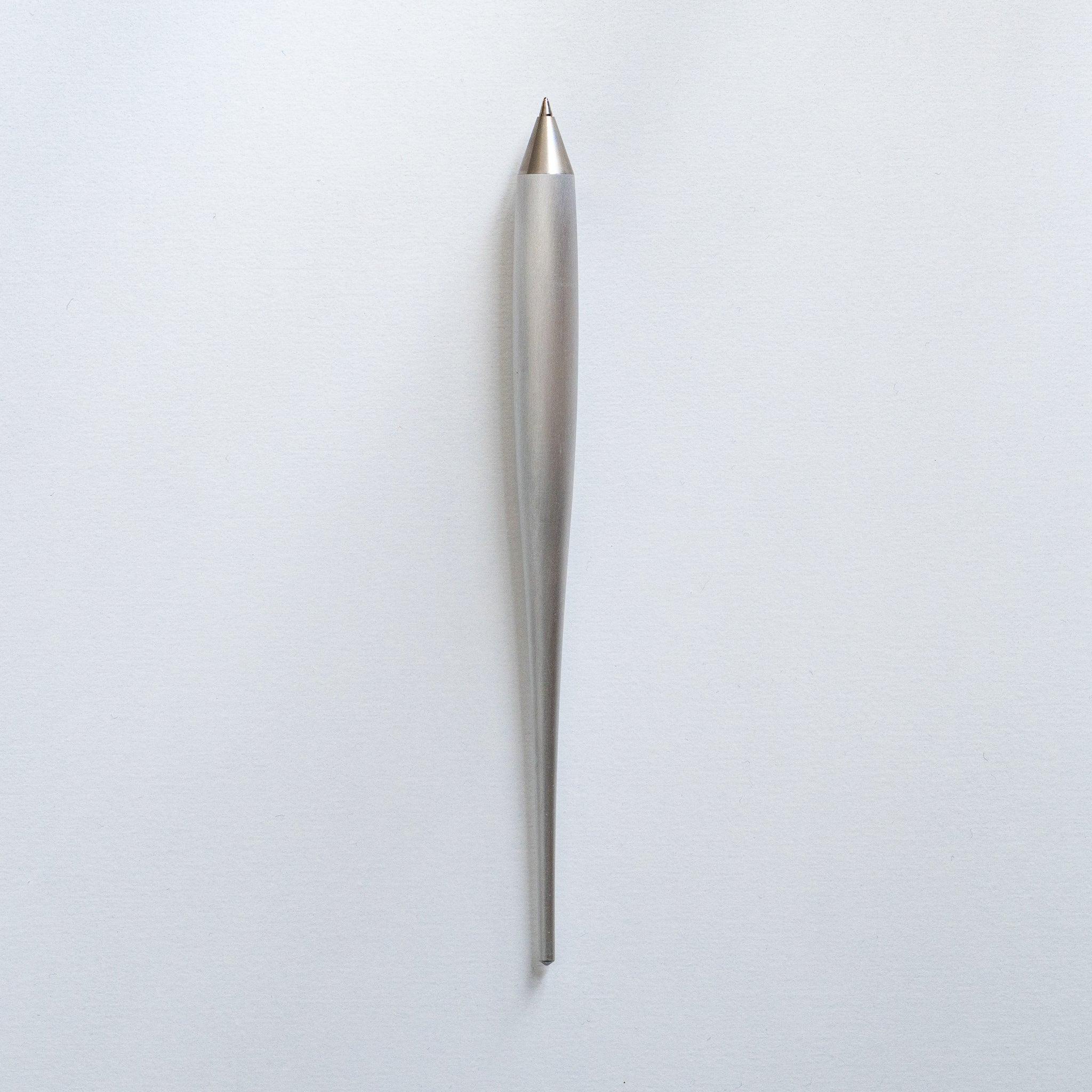 Japanese aerospace-grade duralumin ballpoint pen standing vertically on neutral light gray background surface