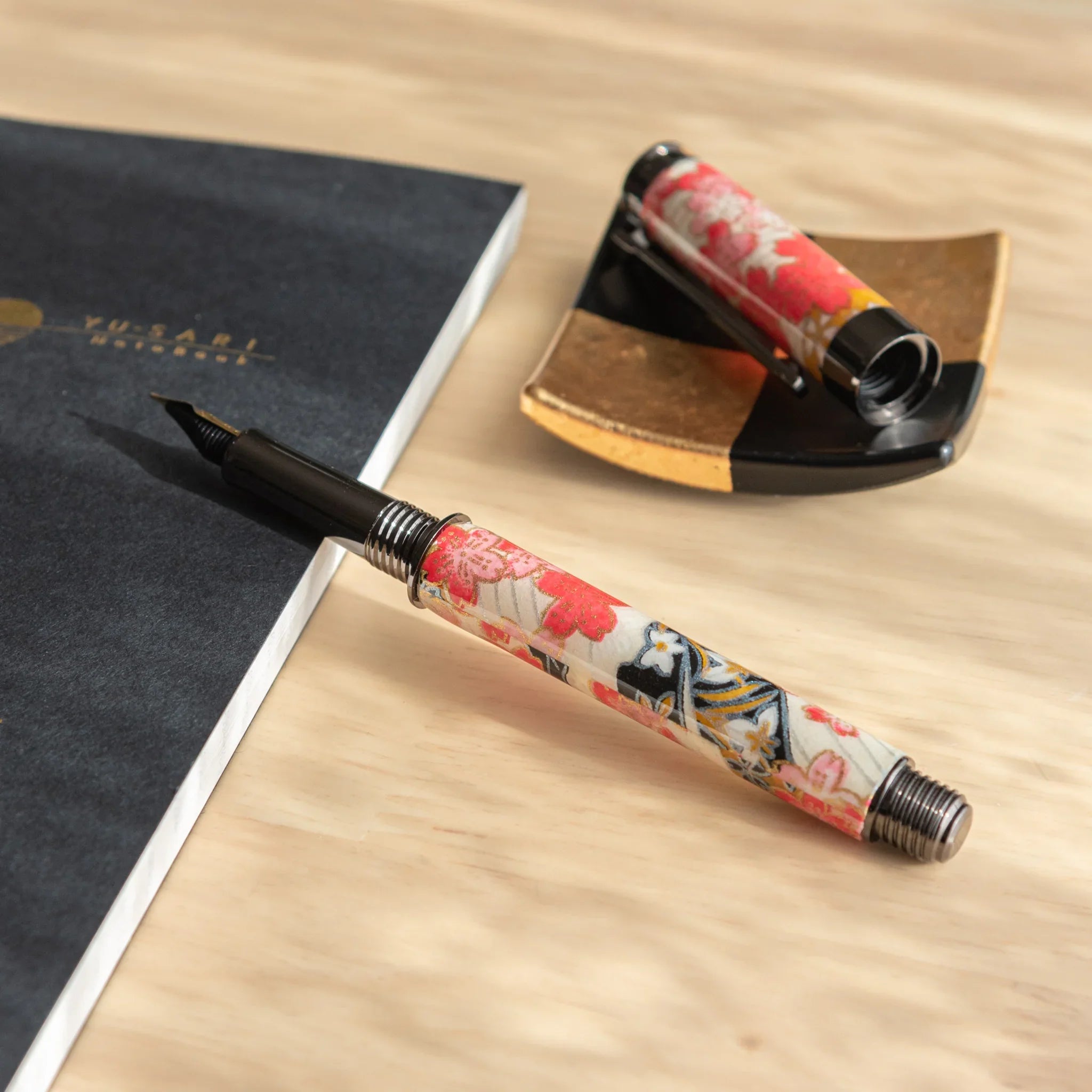 Akebono Cherry Mino Washi fountain pen positioned on cream background with red floral botanical wrapper with nib